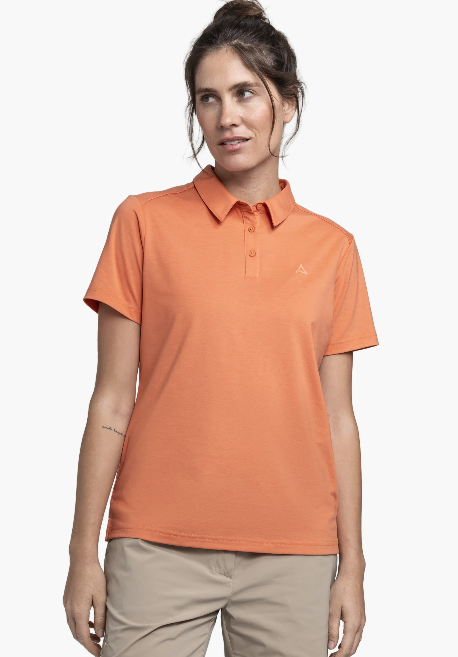 Polo Shirt Ramseck L. Ein weibliches Model steht leicht seitlich und trägt das orange Poloshirt mit sichtbarem Schöffel-Logo auf der linken Brust, vor einem neutralen Hintergrund.