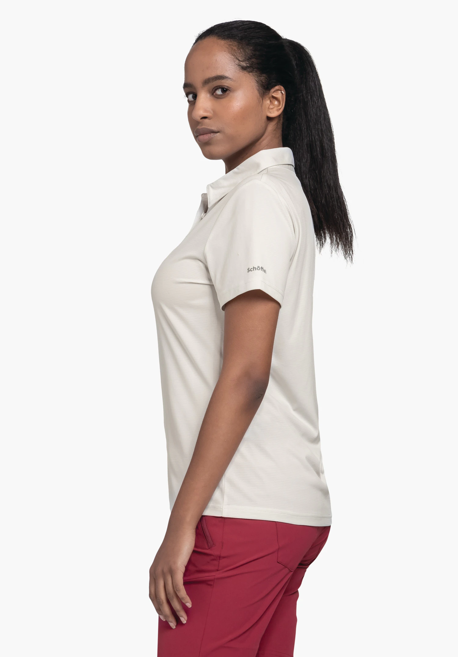 CIRC Polo Shirt Tauron L in de kleur natur wordt gepresenteerd door een model in zijaanzicht voor een neutrale achtergrond. Het subtiele Schöffel-logo is duidelijk zichtbaar op de mouw en onderstreept de sportieve look voor het komende seizoen.