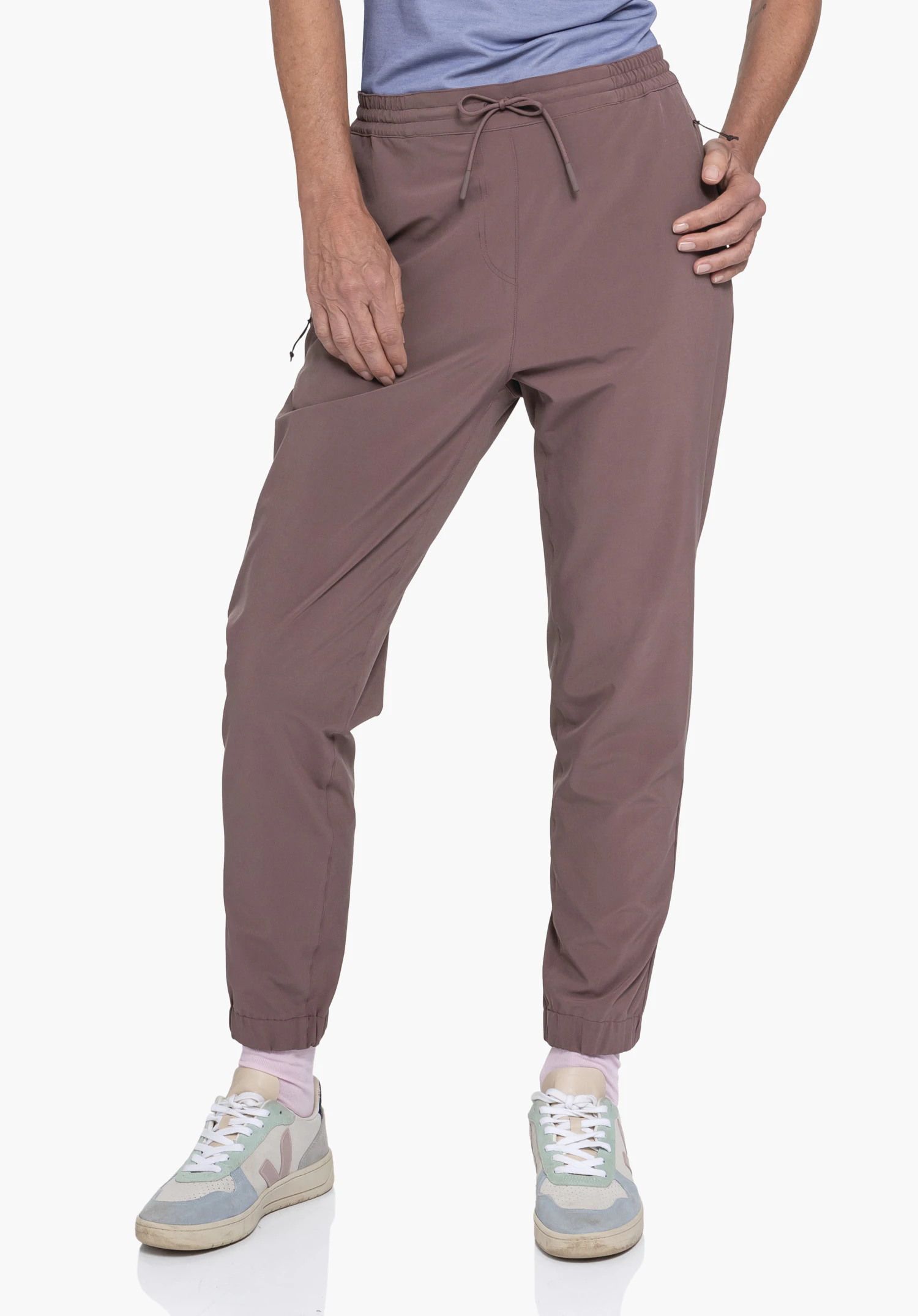 Pants Vienna L in Braun. Das Model steht frontal mit einer Hand an der Hüfte und präsentiert die Vorderseite der Hose vor einem neutralen Hintergrund.