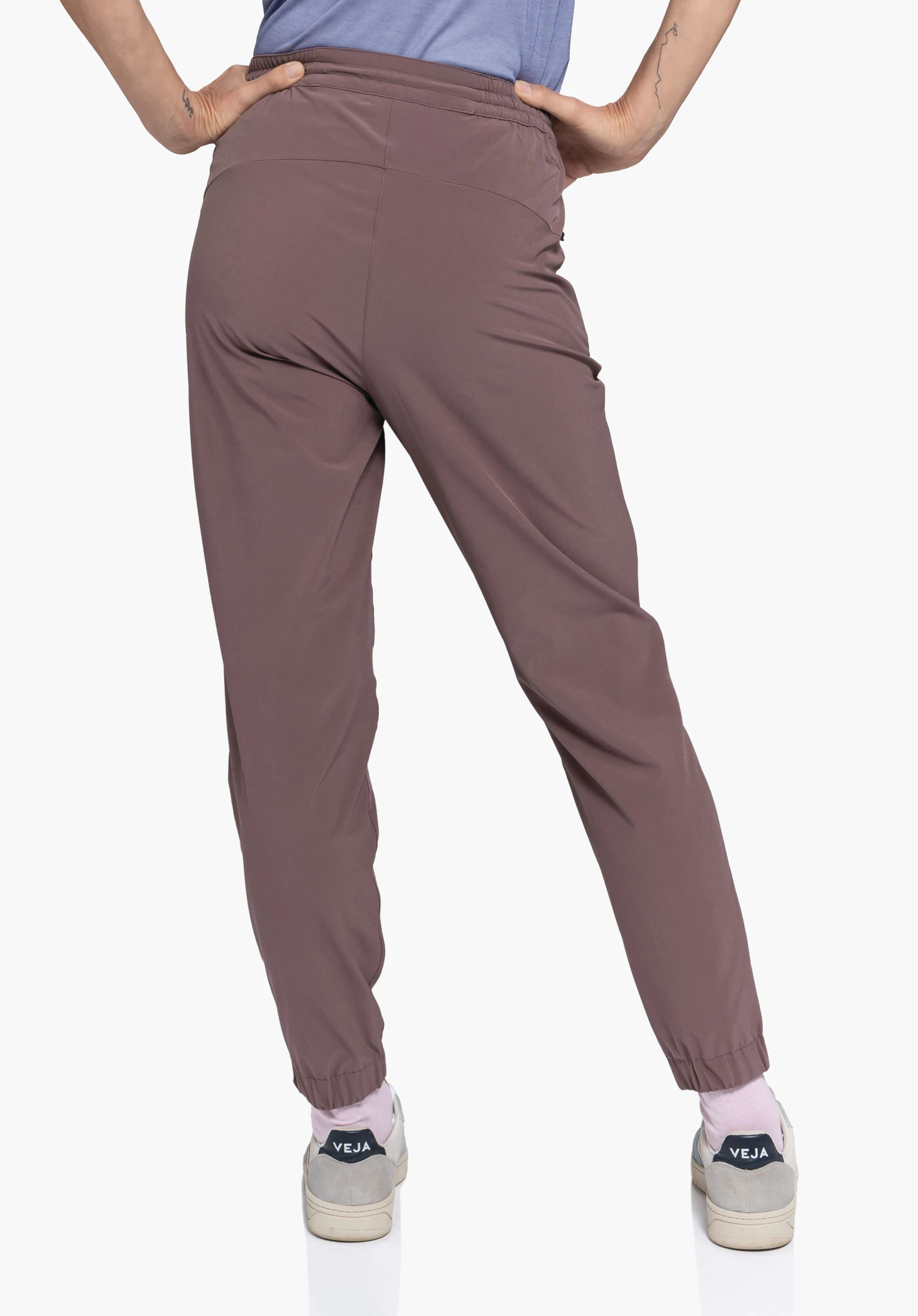 Pants Vienna L in Braun in der Rückenansicht an einem Model mit den Händen an der Hüfte vor neutralem Hintergrund, wobei das Schöffel-Logo dezent auf der Rückseite sichtbar ist.