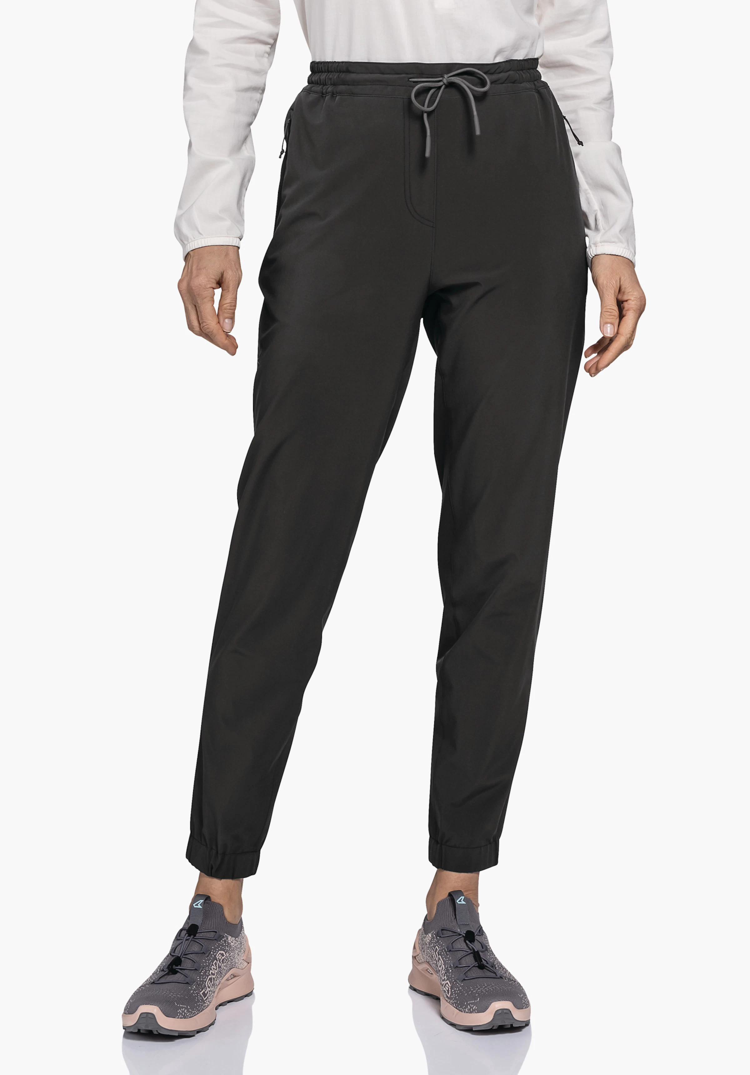 Pants Vienna L gedragen door een model dat frontaal staat. Je ziet de zwarte broek met een elastische tailleband, trekkoord en boordjes aan de broekspijpen tegen een neutrale achtergrond.
