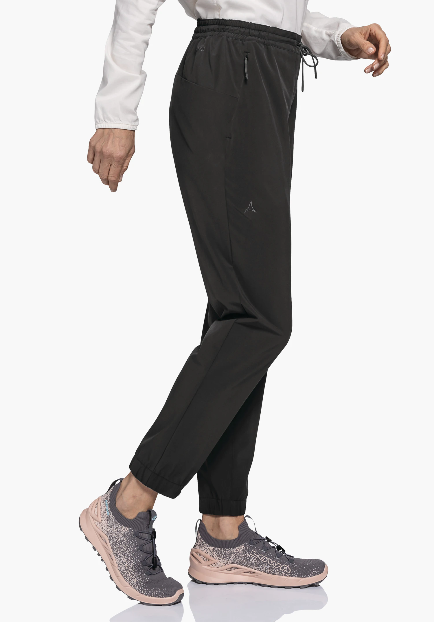 Pants Vienna L in Schwarz, präsentiert in einer dynamischen Seitenansicht auf neutralem Hintergrund. Das Model trägt die Hose mit elastischem Bund und Bündchen am Beinabschluss, während das dezente Schöffel-Logo am Oberschenkel für einen sportiven Look sorgt.