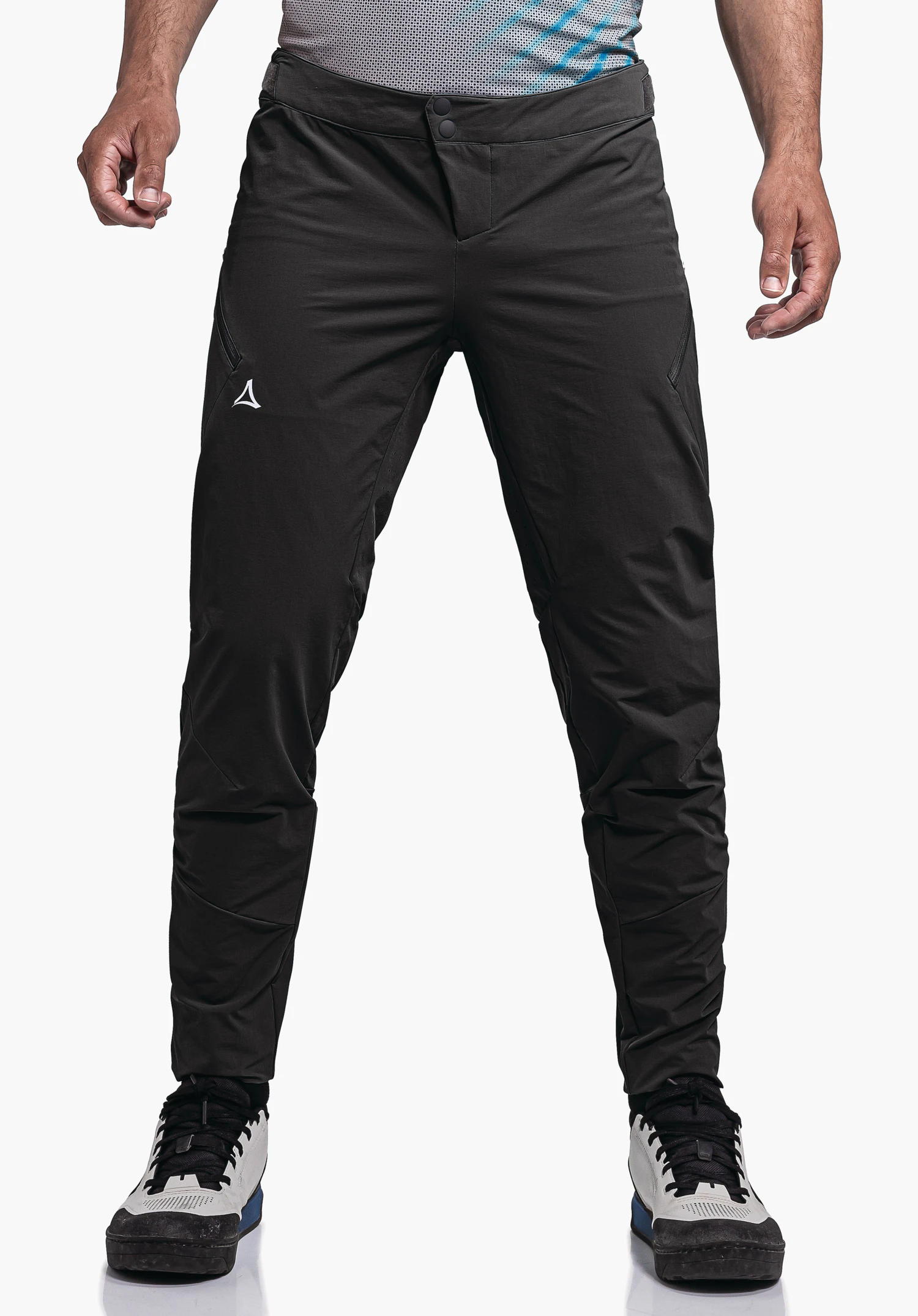 Pants Arosa M pantalon outdoor noir avec logo Schöffel sur la cuisse gauche, porté par une personne debout; t-shirt bleu clair et blanc visible, chaussures blanches et bleu foncé; fond blanc neutre.