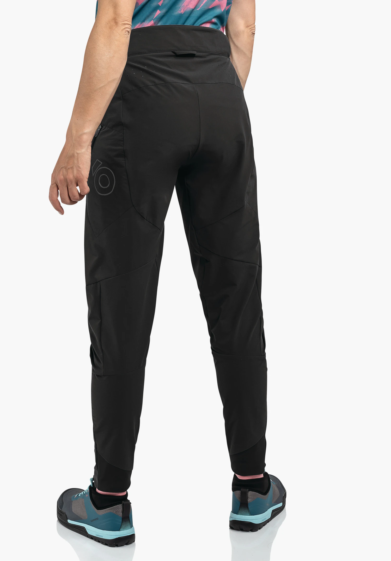 Pants Arosa L black ankle-length trekking trousers worn from the back; person stands relaxed, wearing light blue hiking shoes; white studio background.