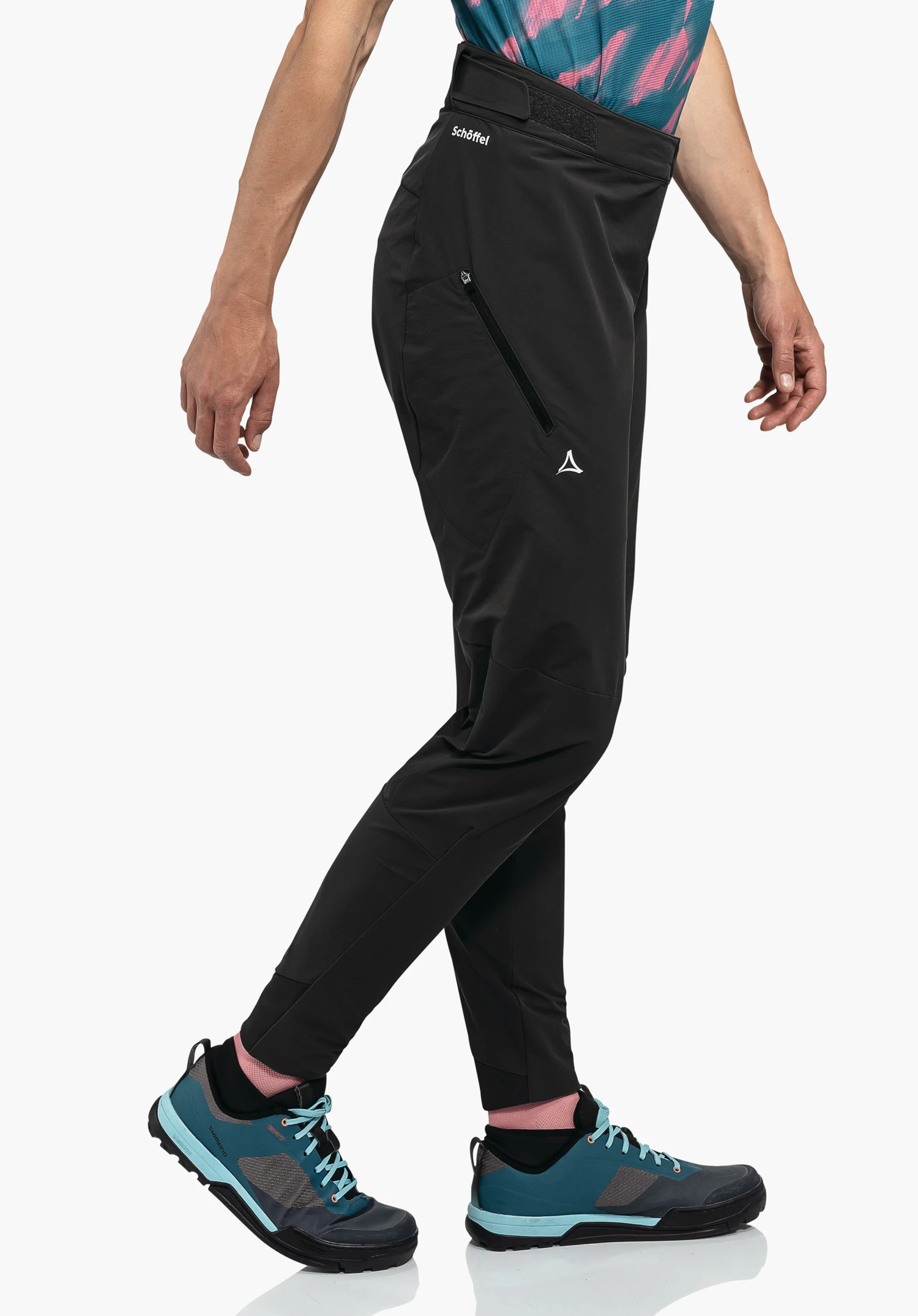 Pants Arosa L black outdoor trousers worn by a person taking a step; white studio background. Hip lettering "Schöffel" and visible Schöffel logo; dark blue shoes with light blue details.