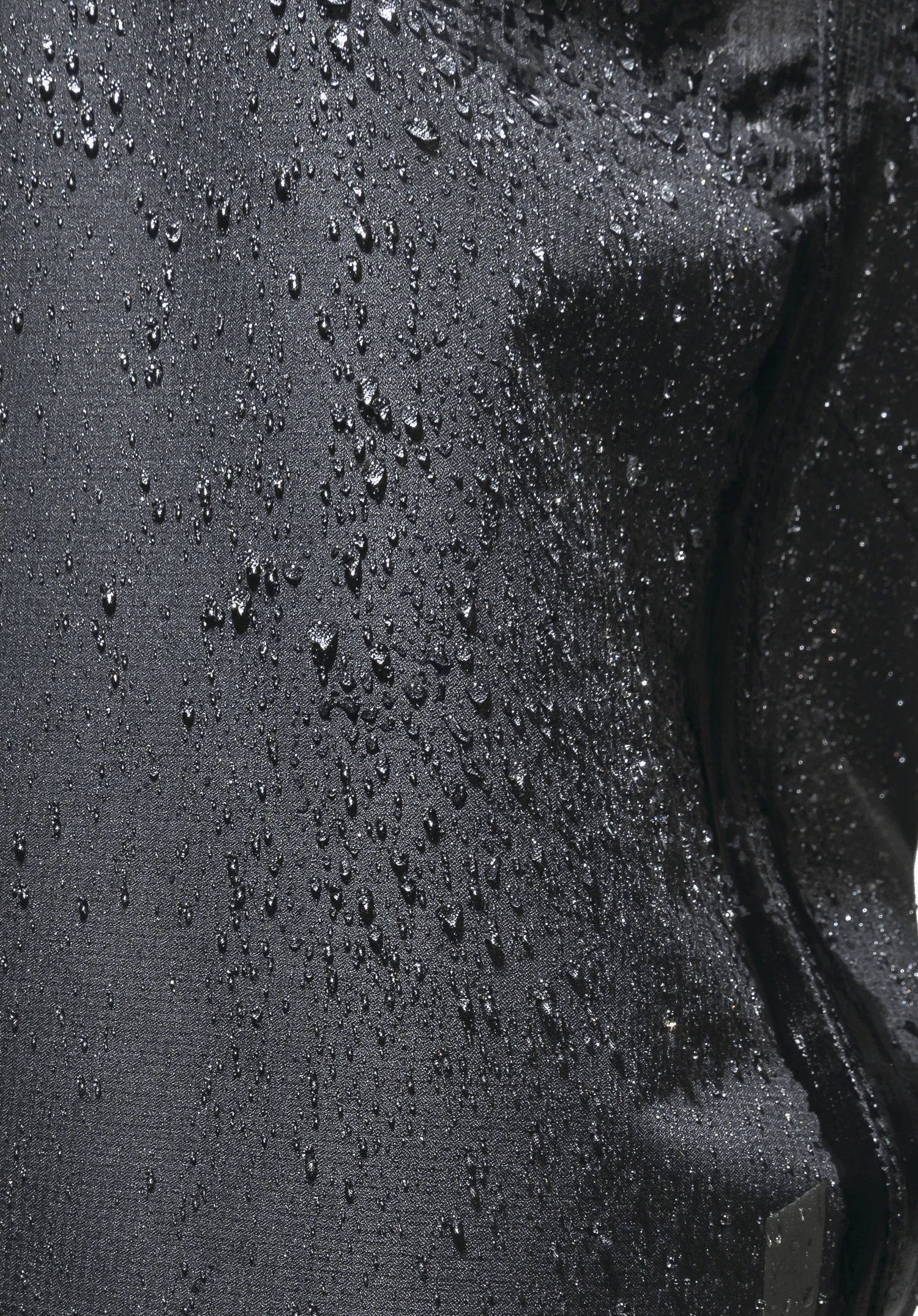 2.5L Pants Tarvis L. Detail view of the black fabric with water droplets demonstrating the water-repellent function, plus a side zip. Close-up against a white background.