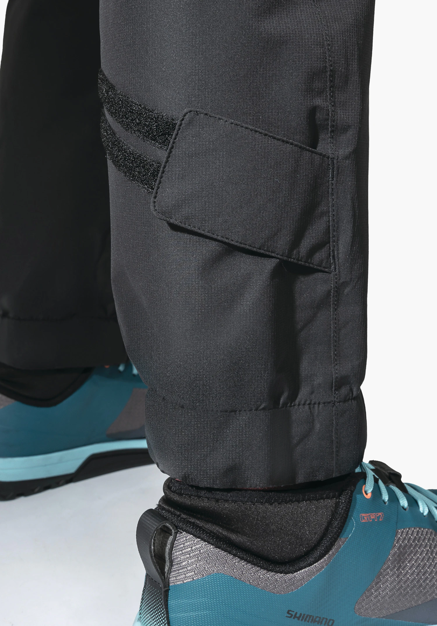 2.5L Pants Tarvis L. Adjustable leg hem with Velcro fastening on the black technical fabric. Close-up against a white/neutral background.