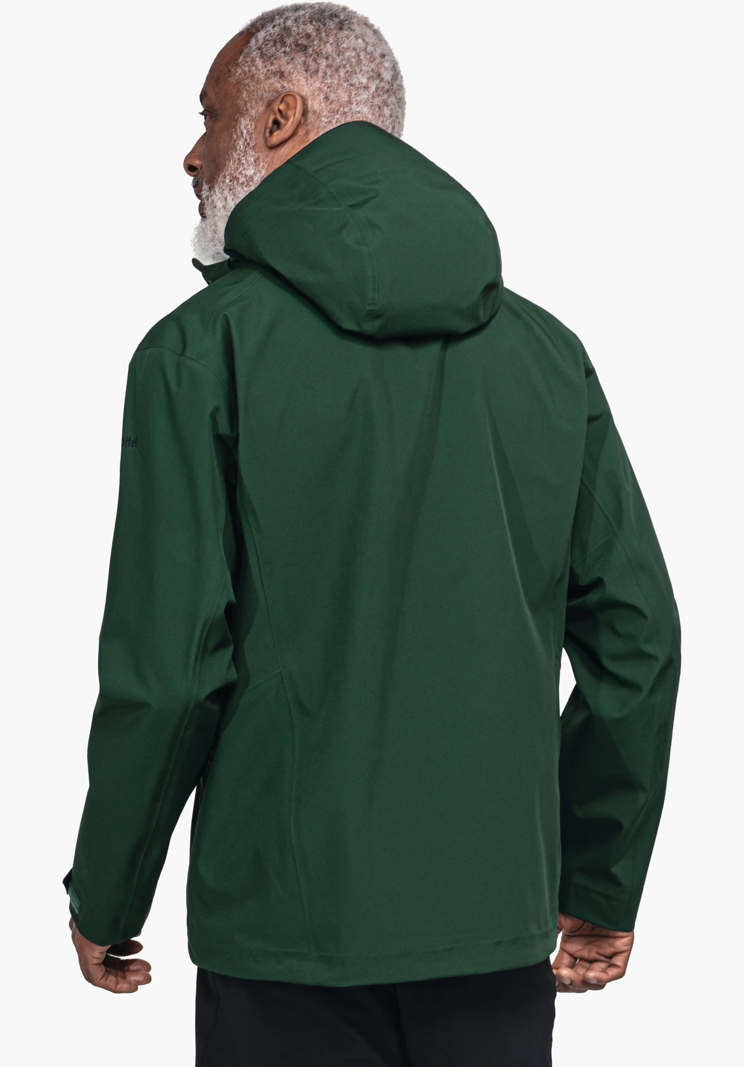 Jacket Style Cascata MNS donkergroene jas met capuchon; een man draagt deze, rug naar de camera, staat voor een witte achtergrond; oudere man met lichtgrijs haar. Tekst op de mouw: "Schöffel".