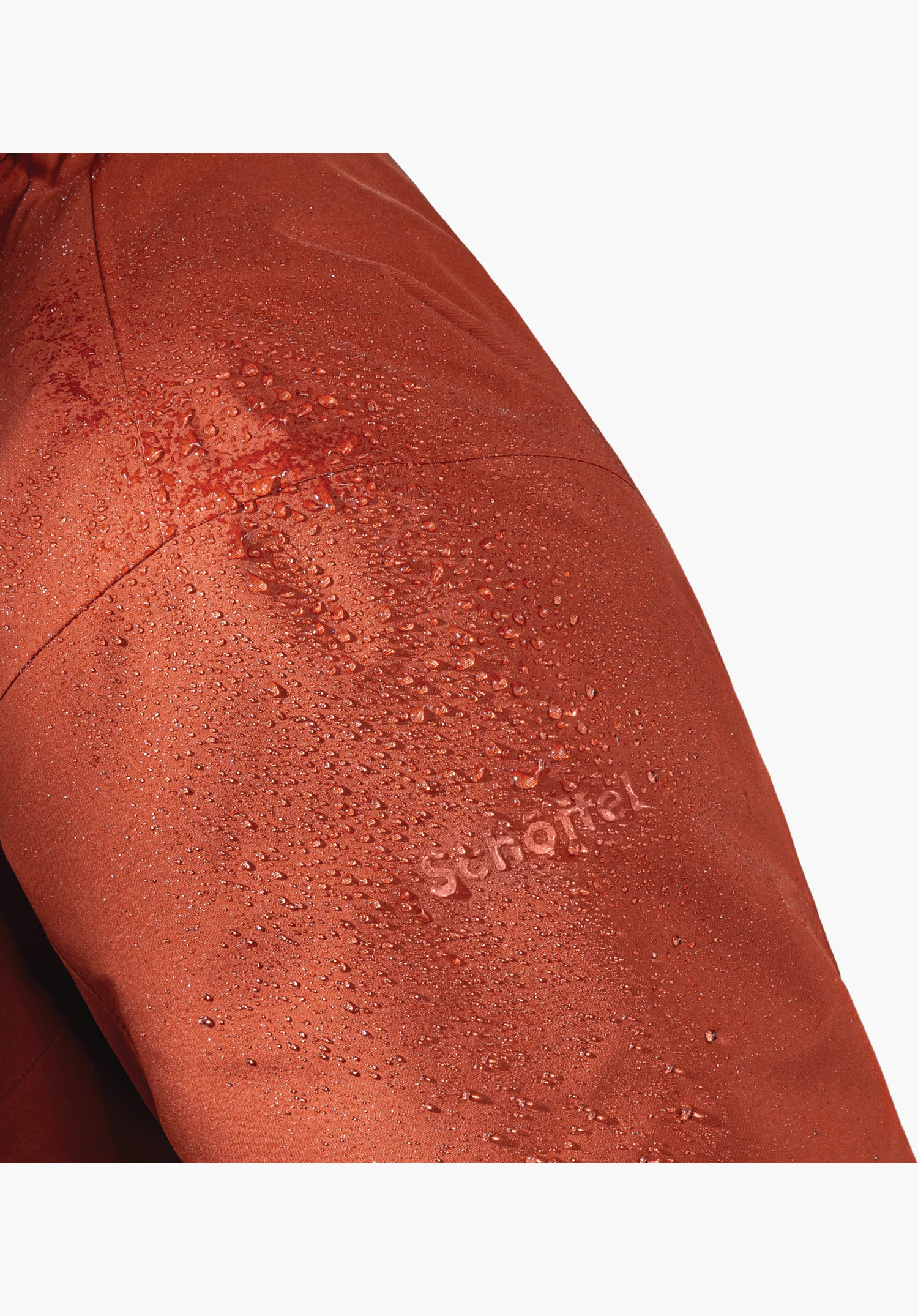 3in1 Jacket Style Tamina MNS zeigt die wasserabweisende Oberfläche des roten Stoffs mit Wassertropfen und dem Schöffel-Schriftzug als Nahaufnahme vor weißem Hintergrund.