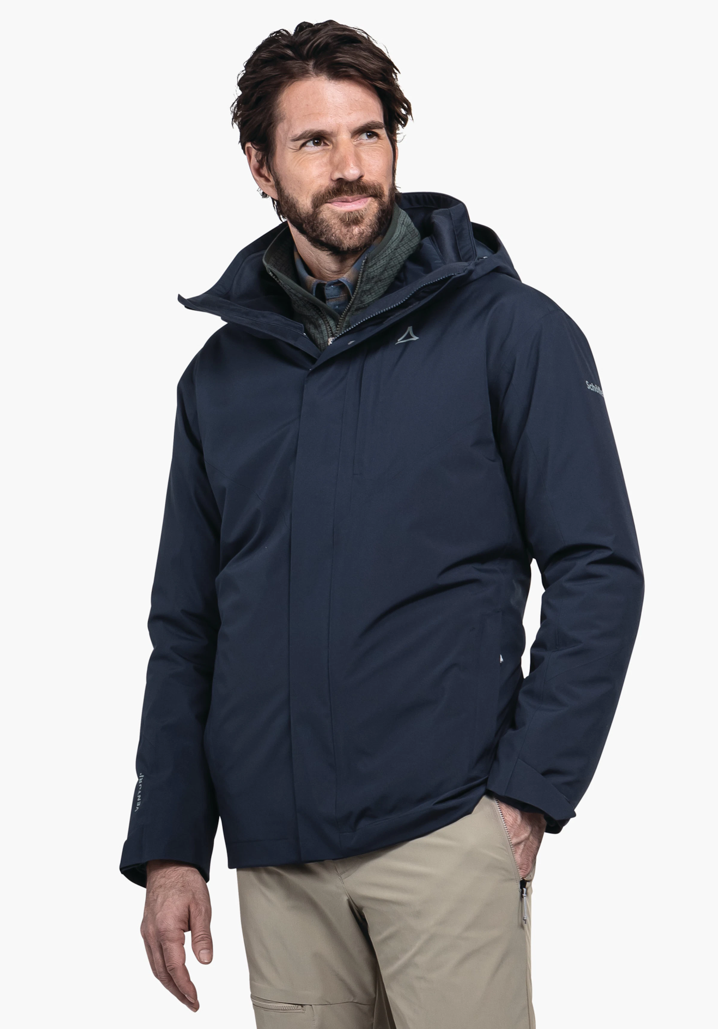 3in1 Jacket Style Tamina MNS Dunkelblaue Outdoorjacke, von einem Mann getragen, der nach rechts blickt; Schöffel-Logo auf der Brust, dunkelgrüne Innenlage, beige Hosen, weißer Hintergrund. Text: "Schöffel".