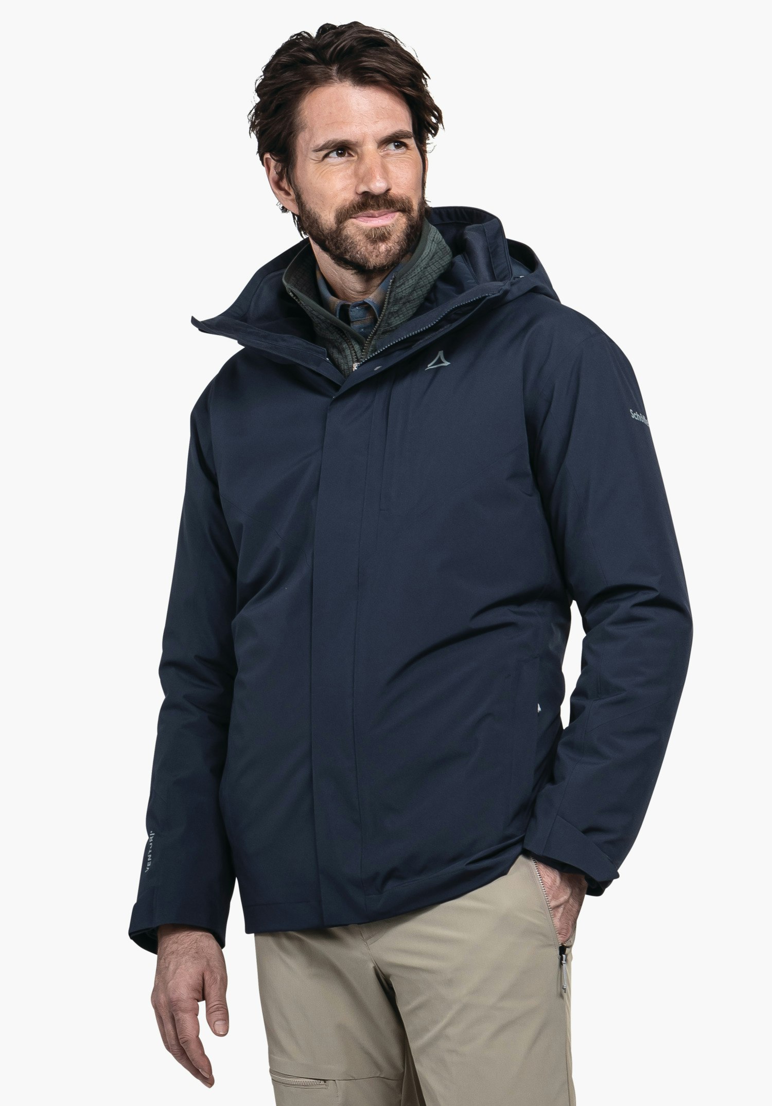 3in1 Jacket Style Tamina MNS Dunkelblaue Outdoorjacke, von einem Mann getragen, der nach rechts blickt; Schöffel-Logo auf der Brust, dunkelgrüne Innenlage, beige Hosen, weißer Hintergrund. Text: "Schöffel".
