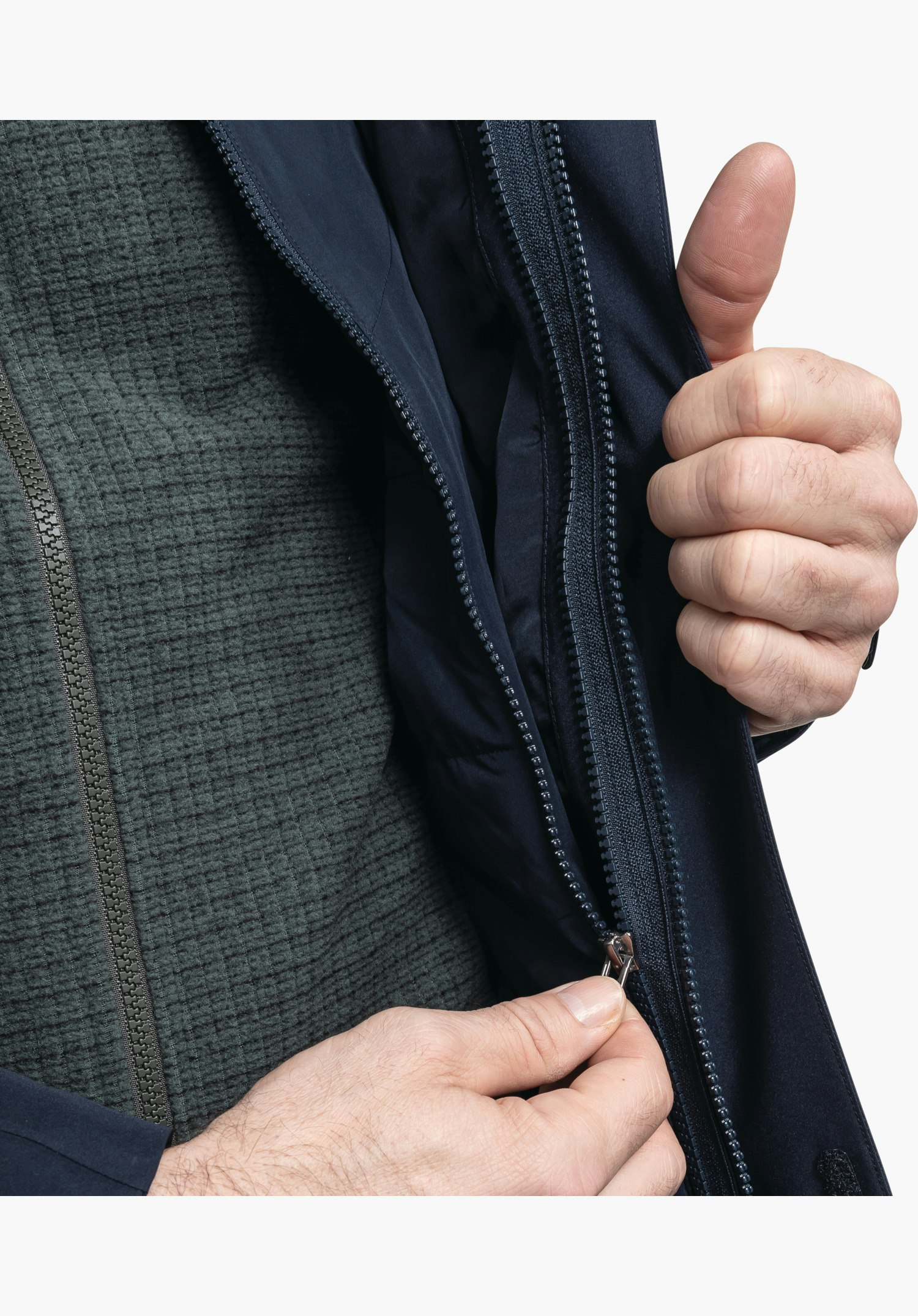 3in1 Jacket Style Tamina MNS zeigt den robusten Frontreißverschluss der blauen Außenjacke, während Hände die Jacke öffnen und die texturierte Innenlage sichtbar machen, Nahaufnahme vor weißem Hintergrund.