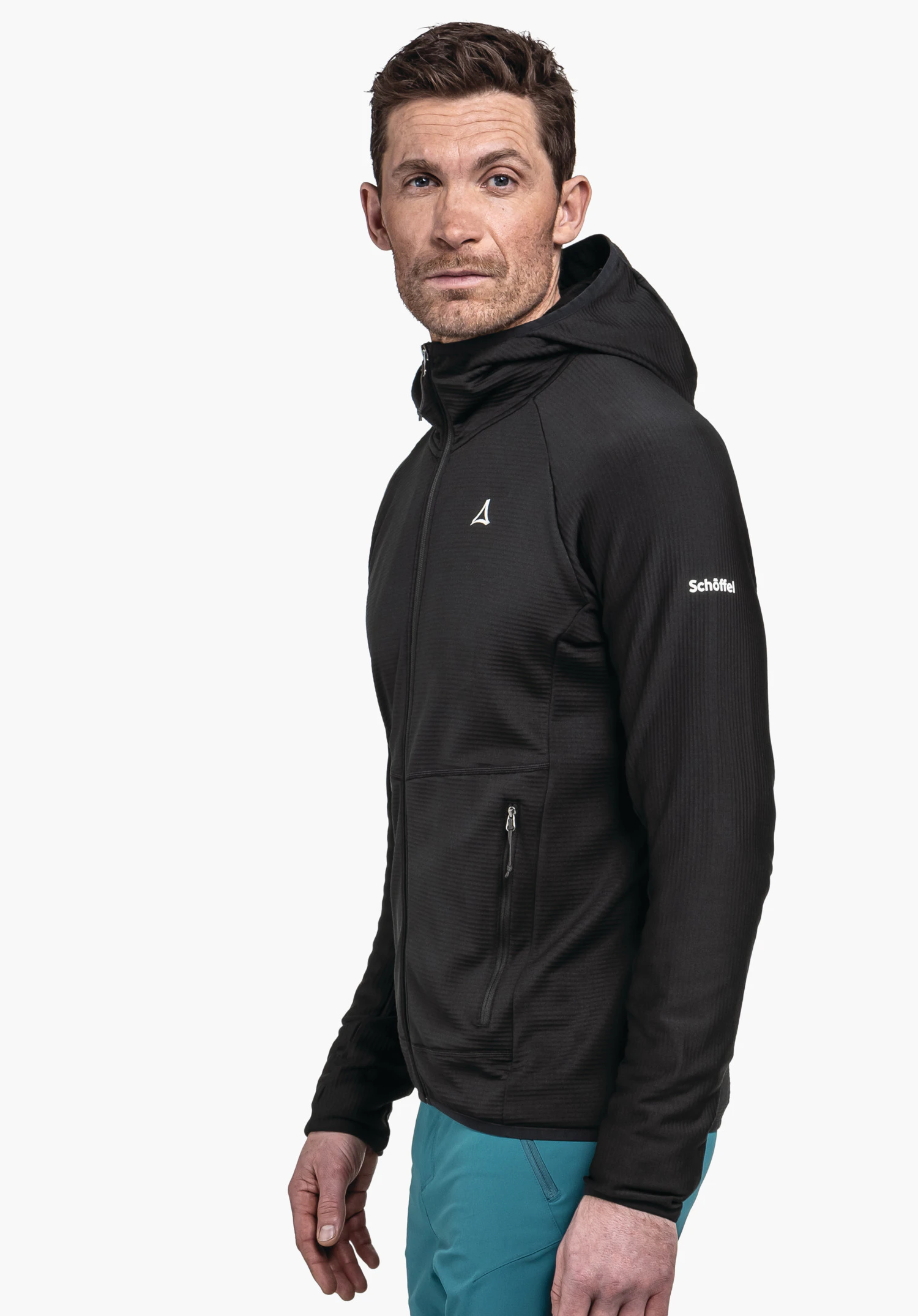 Fleece Hoody Style Cascata MNS in der Farbe schwarz. Ein Model steht seitlich in die Kamera blickend vor einem neutralen Hintergrund. Die Jacke besticht durch ihre funktionale Passform, das markante Schöffel-Logo auf dem Oberarm sowie ein diskretes Logo-Element auf der Brust.