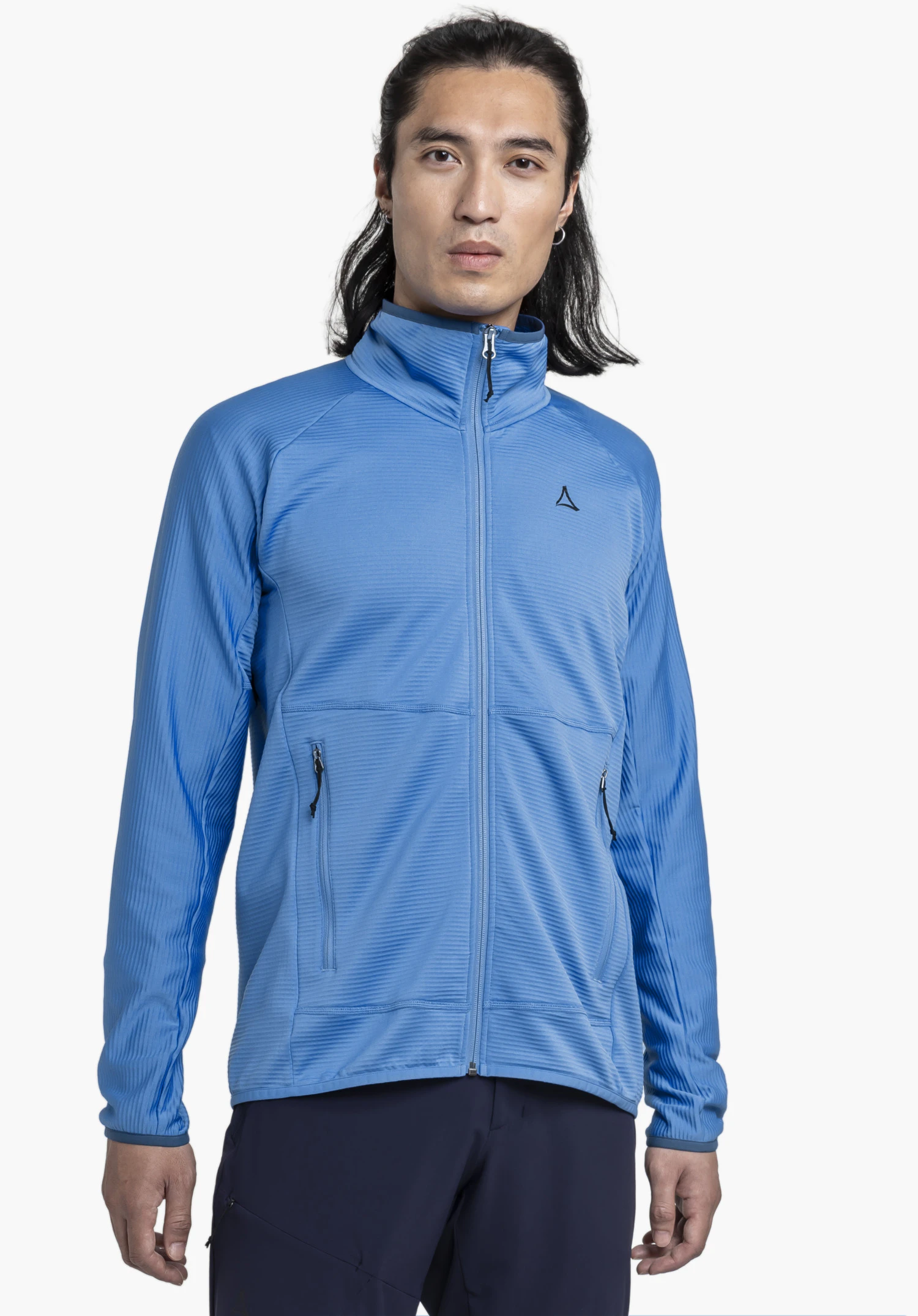 Fleece Jk Style Cascata MNS getragen von einem Model, das frontal steht. Die blaue Jacke zeigt einen hochgeschlossenen Kragen sowie das Schöffel-Logo auf der linken Brust. Das Bild ist vor einem neutralen Hintergrund aufgenommen.