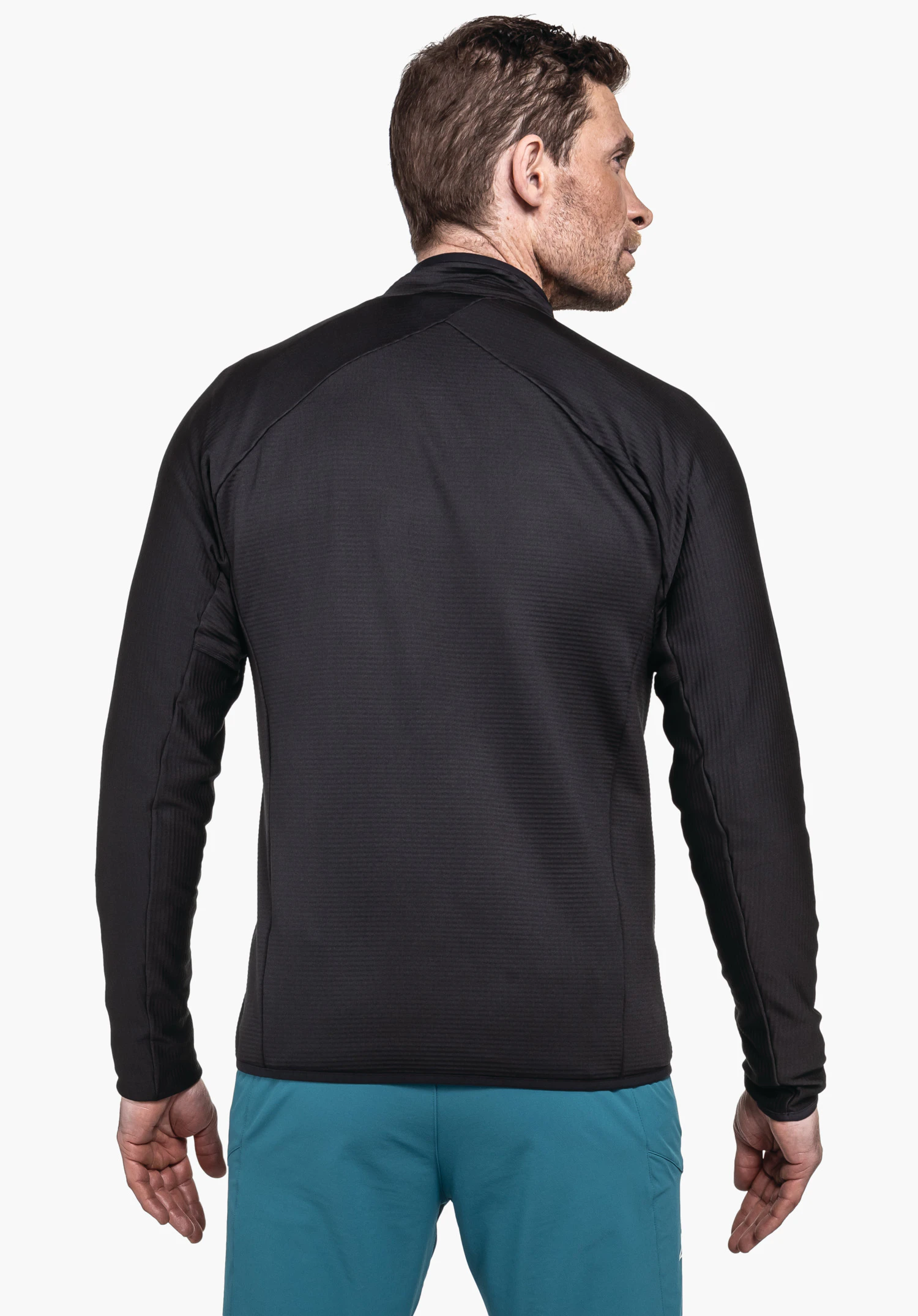 Fleece Jk Style Cascata MNS black jacket seen on the back of a standing man looking sideways; hands relaxed; light blue trousers; neutral light background.