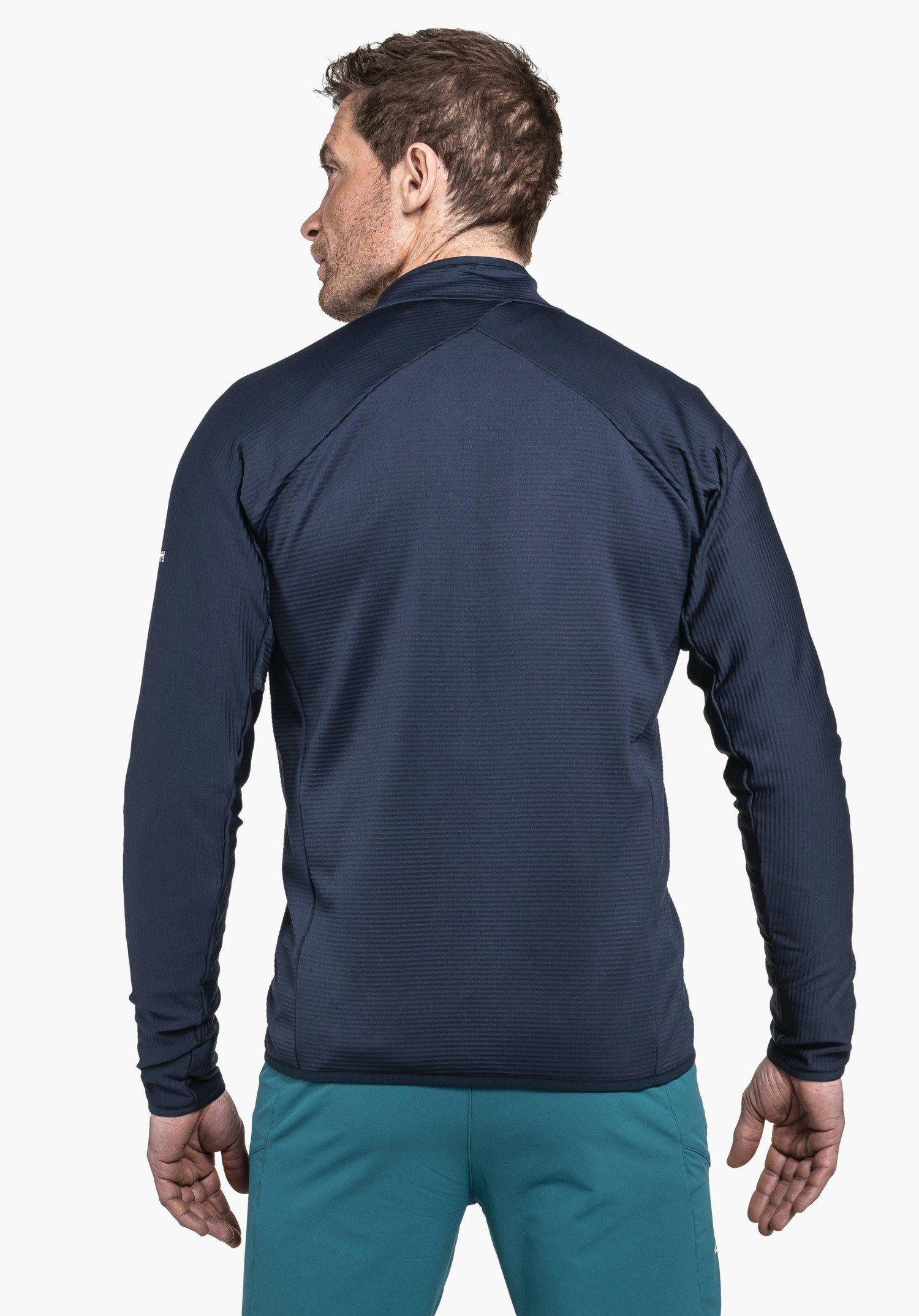 Fleece Jk Style Cascata MNS Dunkelblaue Jacke, getragen vom männlichen Modell, Rücken zur Kamera, Kopf nach links gedreht; trägt türkise Hose; neutraler weißer Hintergrund.