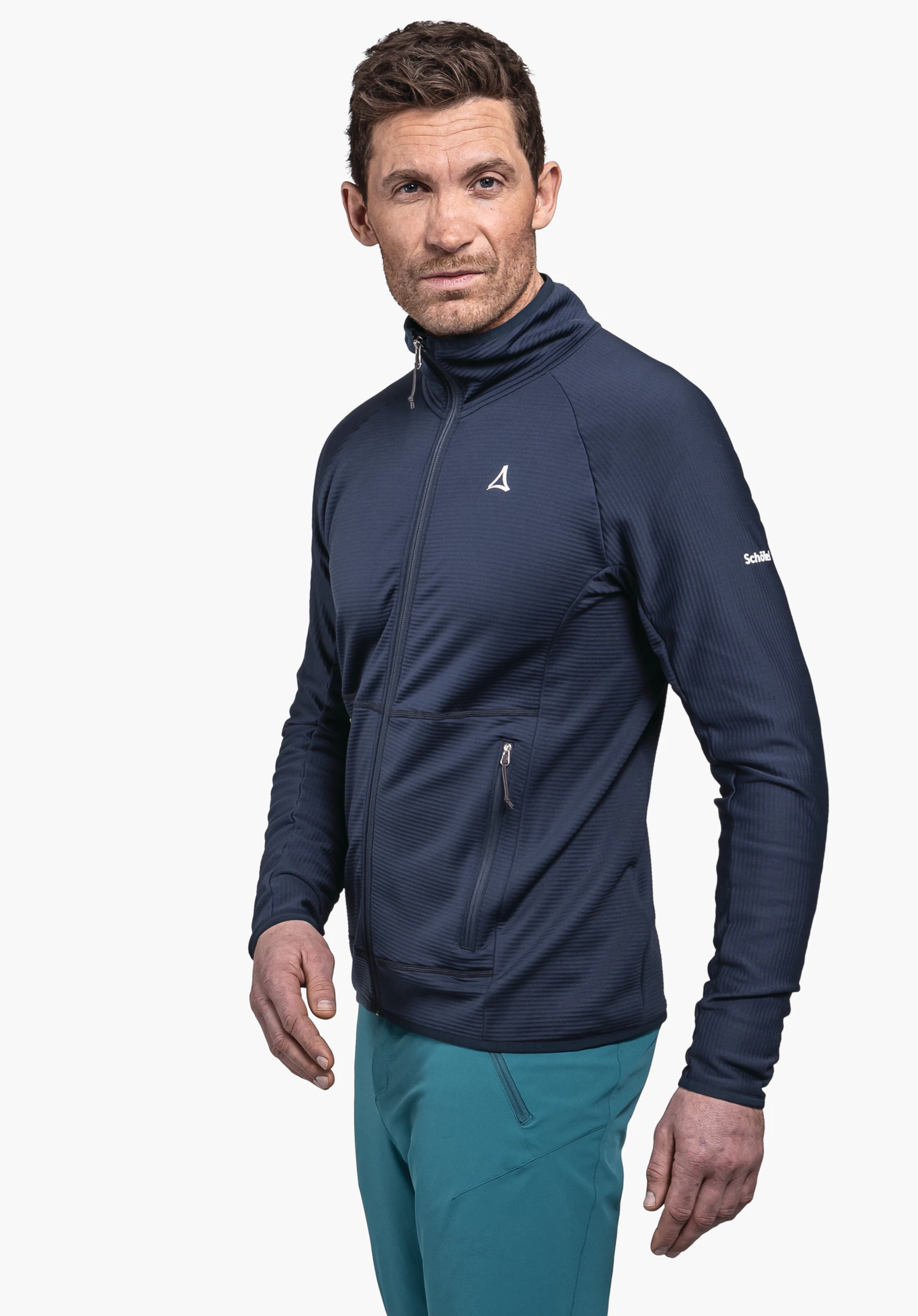 Fleece Jk Style Cascata MNS dark blue jacket with Schöffel logo; man wears it, stands angled and looks to the side, wears turquoise trousers in front of a white background. Text: "Schöffel".