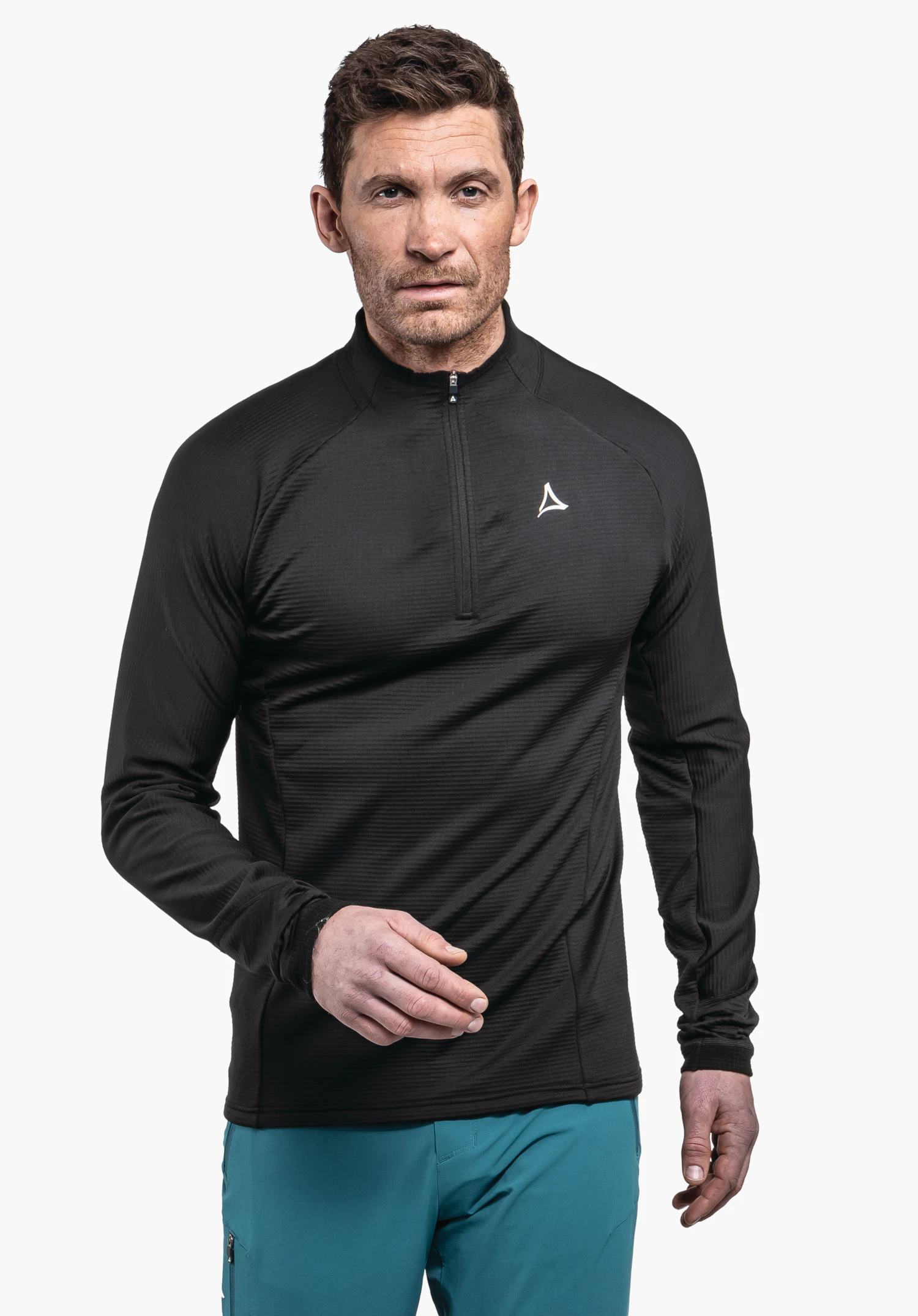 Longsleeve Style Cascata MNS man wearing a black long-sleeve half-zip shirt (with Schöffel logo), walking slightly forward; neutral light grey background, light blue trousers.
