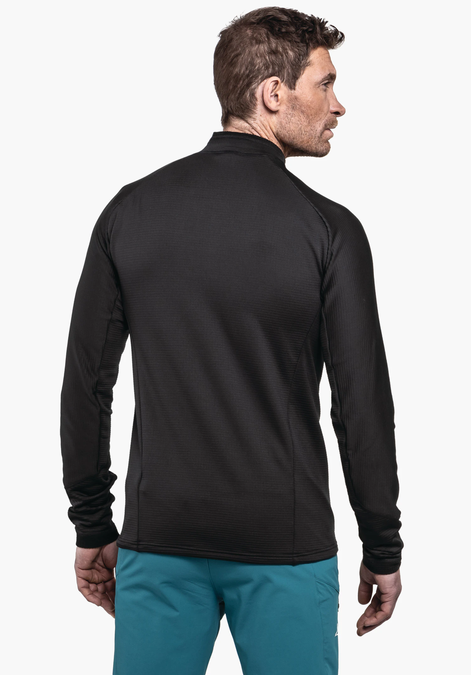 Longsleeve Style Cascata MNS man wearing a black long-sleeve shirt stands with his back to the camera and looks right; light blue trousers with Schöffel logo; white background.