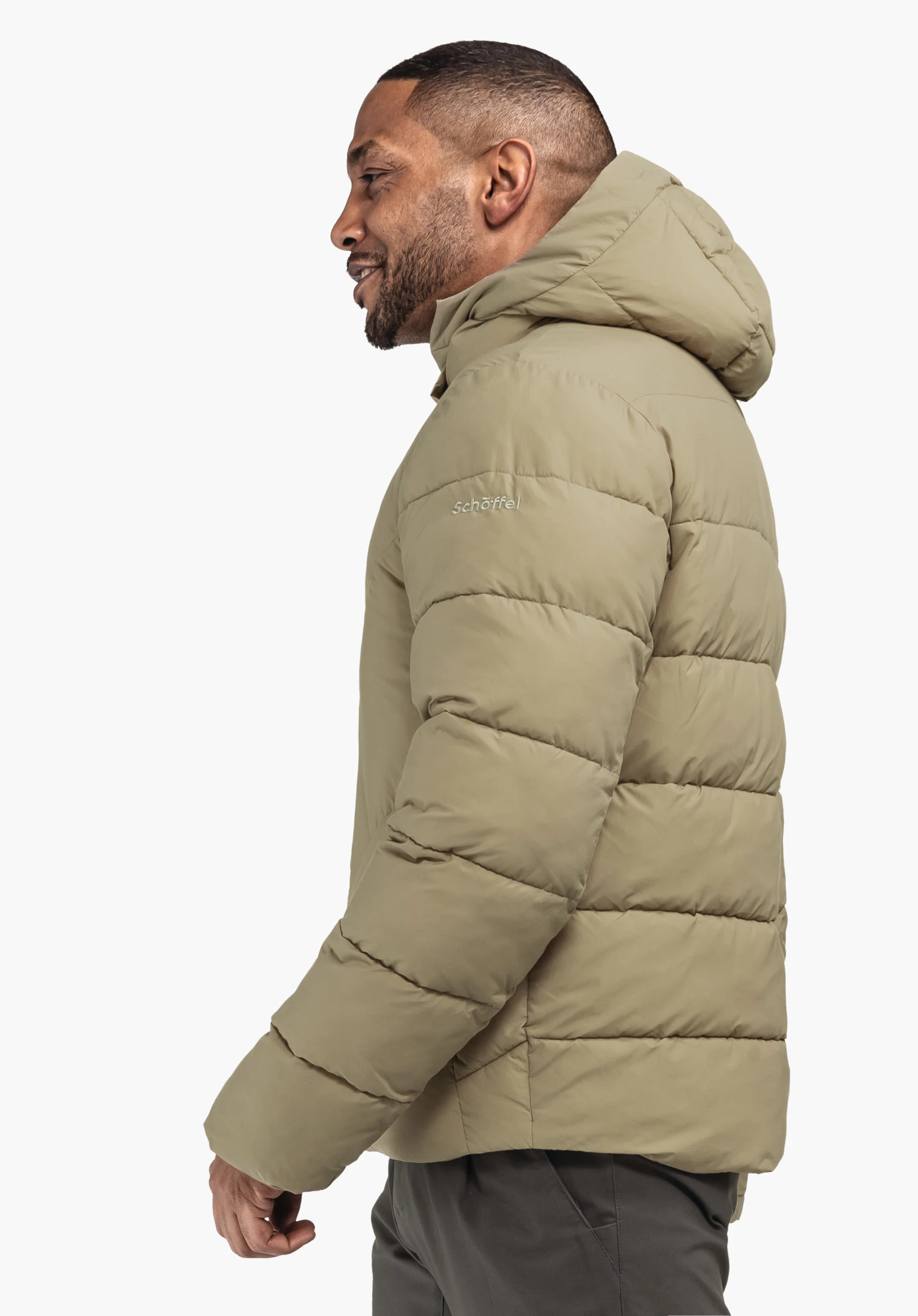 Ins Jacket Style Lodos MNS hellgrüne Steppjacke, ein Mann trägt sie seitlich gewandt und lächelnd mit hochgezogener Kapuze; Studiohintergrund weiß. Text auf Ärmel: "schöffel".
