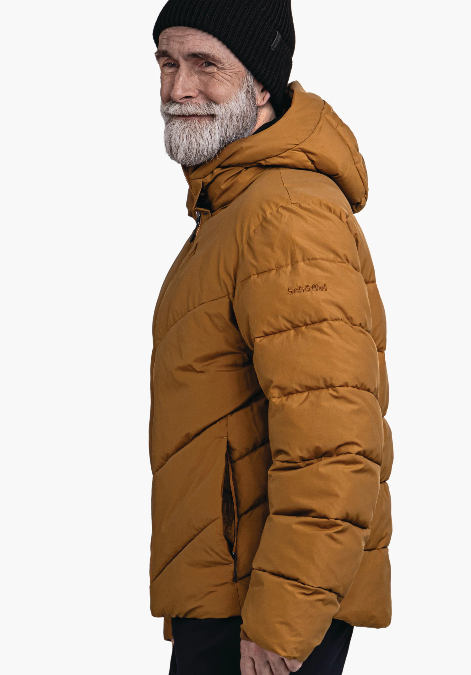 Ins Jacket Style Lodos MNS donkergele donsjas, zijwaarts gedragen door een oudere man die licht glimlacht; draagt een zwarte beanie en witte baard, witte achtergrond. Tekst op de mouw: schöffel.