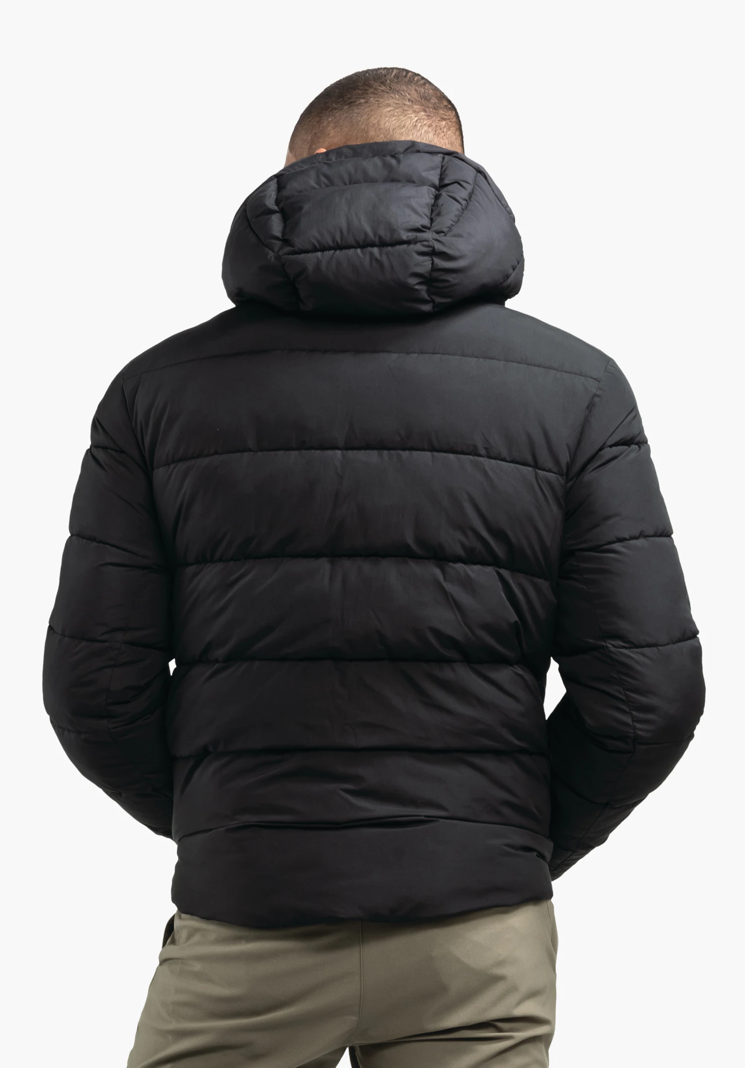 Ins Jacket Style Lodos MNS veste matelassée noire avec capuche; une personne la porte et se tient dos à la caméra devant un fond studio blanc.