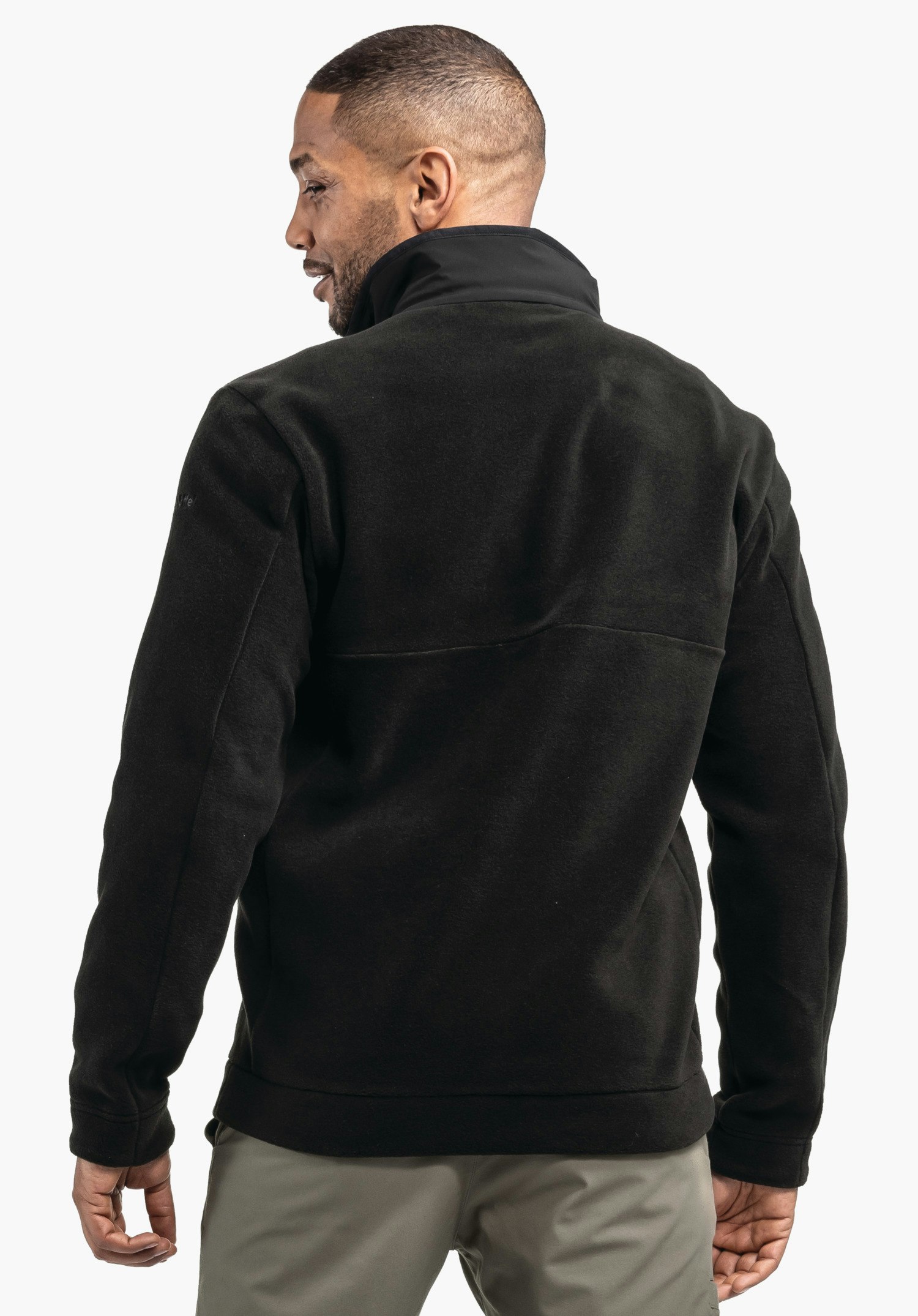 Fleece Jk Style Gregale MNS Schwarze Fleecejacke – getragen von einer Person mit dem Rücken zur Kamera – vor weißem Hintergrund; hellgraue Hosen sichtbar.