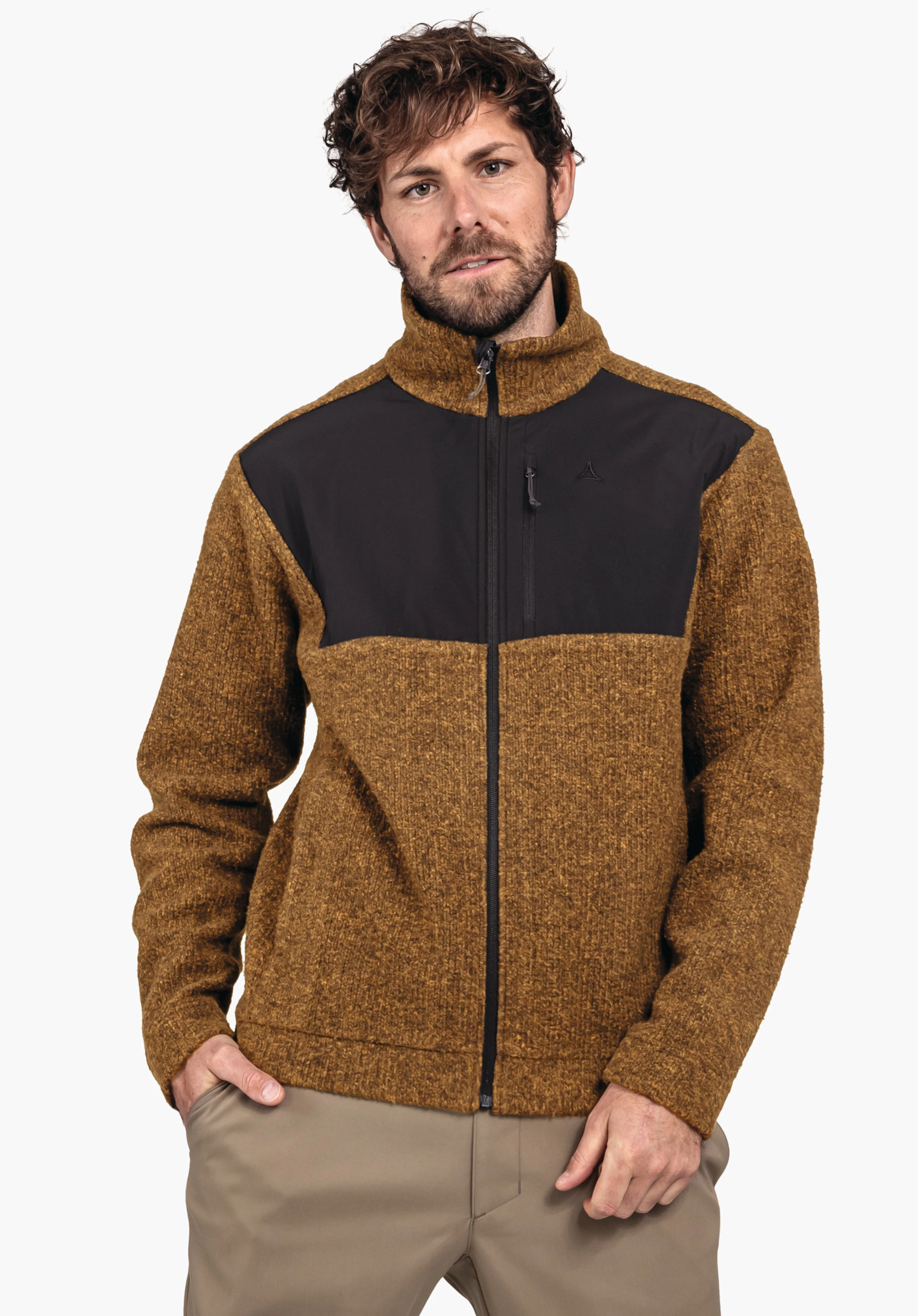 Fleece Jk Style Canterbury MNS Fleecejacke in dunkelgelb mit schwarzem Brustbesatz und Schöffel-Logo; Mann trägt sie geschlossen, Hände in Hosentaschen, leicht geneigt, vor weißem Hintergrund.
