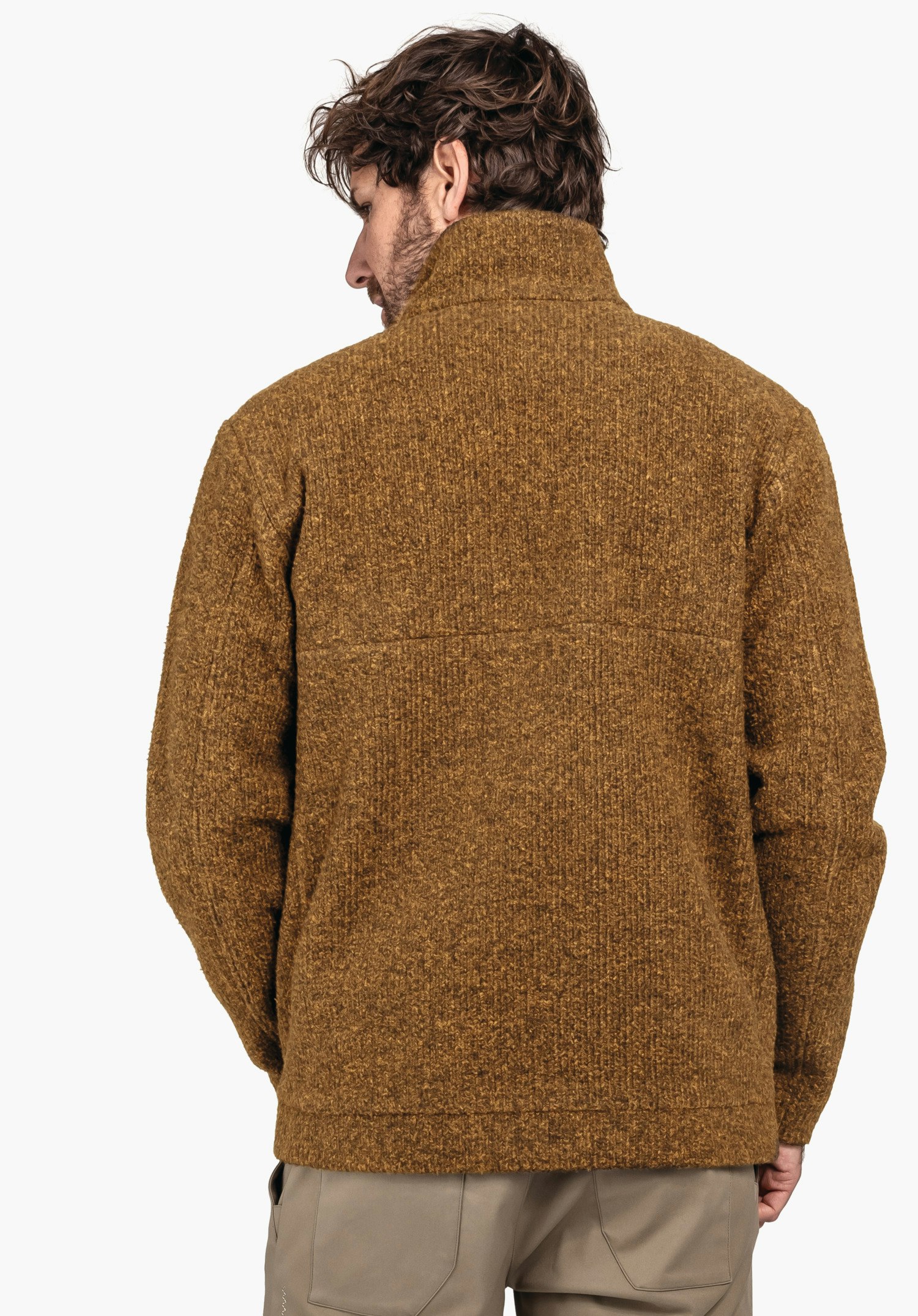 Fleece Jk Style Canterbury MNS dunkelgelbe Strickjacke, getragen von einem Mann, steht mit dem Rücken zum Betrachter; locker sitzend, Hände teilweise in den Taschen; schlichter weißer Hintergrund.