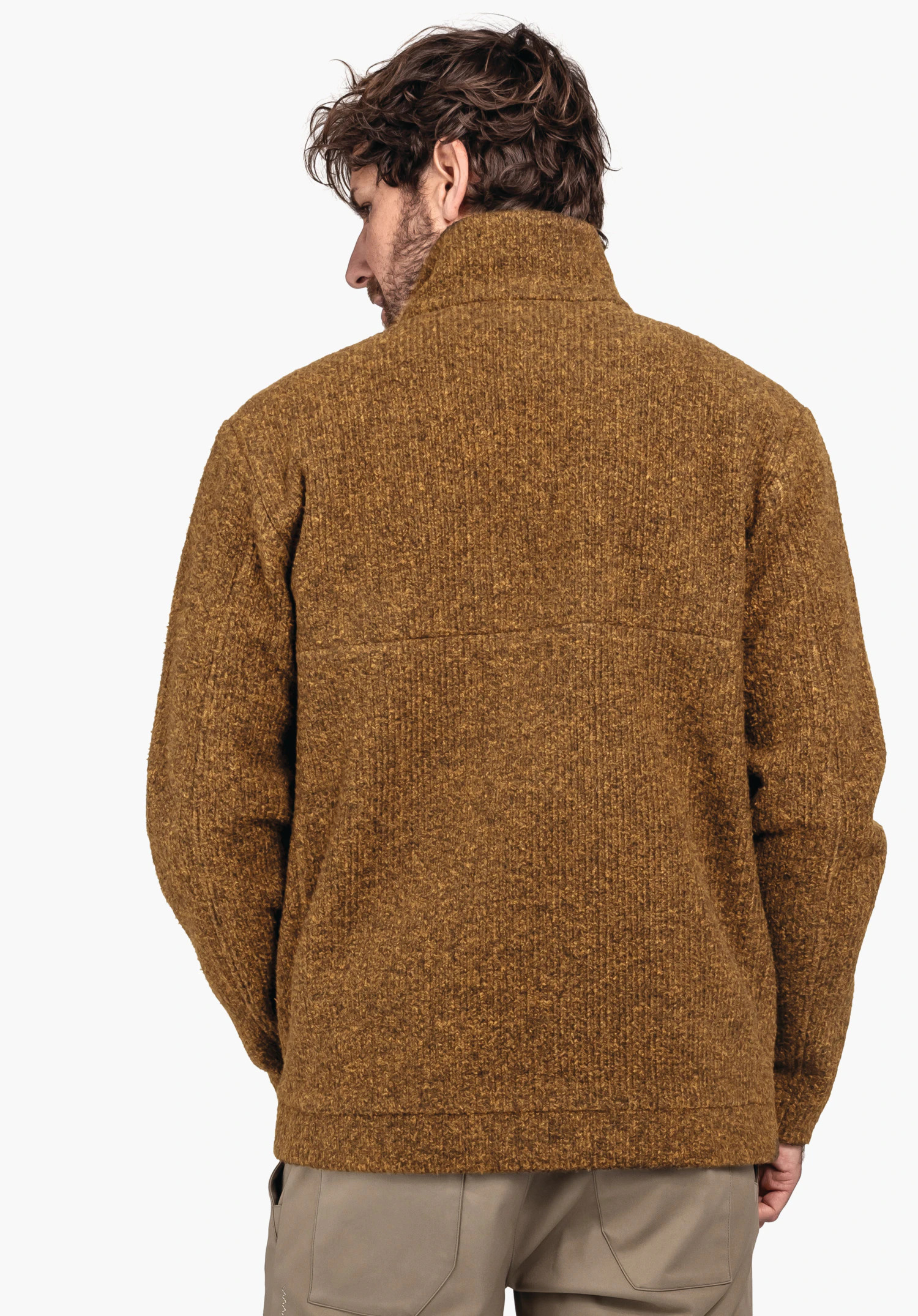 Fleece Jk Style Canterbury MNS dark yellow knitted jacket worn by a man standing with his back to the viewer; loose fit, hands partly in pockets; plain white background., Fleece Jk Style Canterbury MNS dark yellow knitted jacket worn by a man standing with his back to the viewer; loose fit, hands partly in pockets; plain white background.