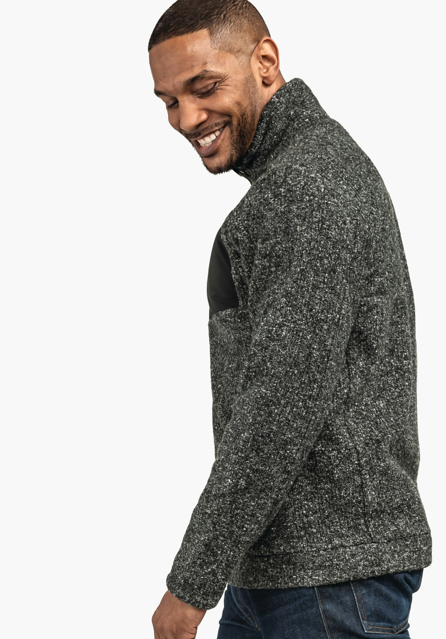 Fleece Jk Style Canterbury MNS Mann trägt gestrickten Pullover mit hohem Kragen, lächelt und blickt zur Seite; steht im Halbprofil vor schlichtem, einfarbigem Hintergrund.