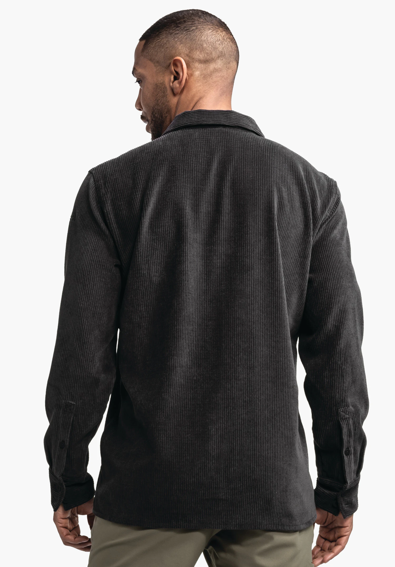 Shirt Style Lodos MNS Dunkelgraues Cordhemd, getragen von einer stehenden Person mit Rücken zur Kamera, Kopf leicht nach links gedreht; heller Studiohintergrund, lange Ärmel mit geknöpften Manschetten.