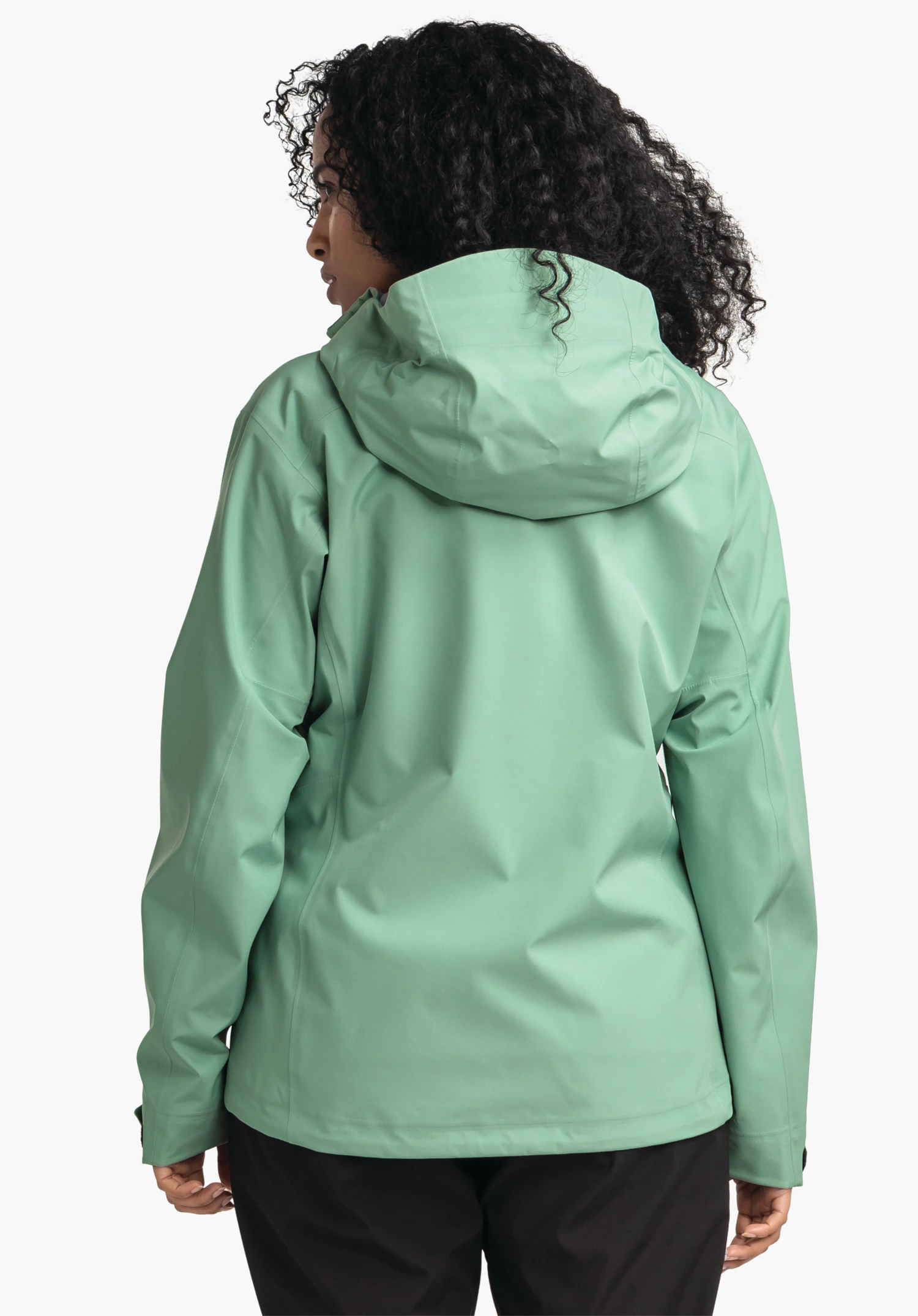 Jacket Style Cascata WMS light green rain jacket worn by a person; rear view with hood up; standing pose, curly black hair visible, black trousers; neutral light background.