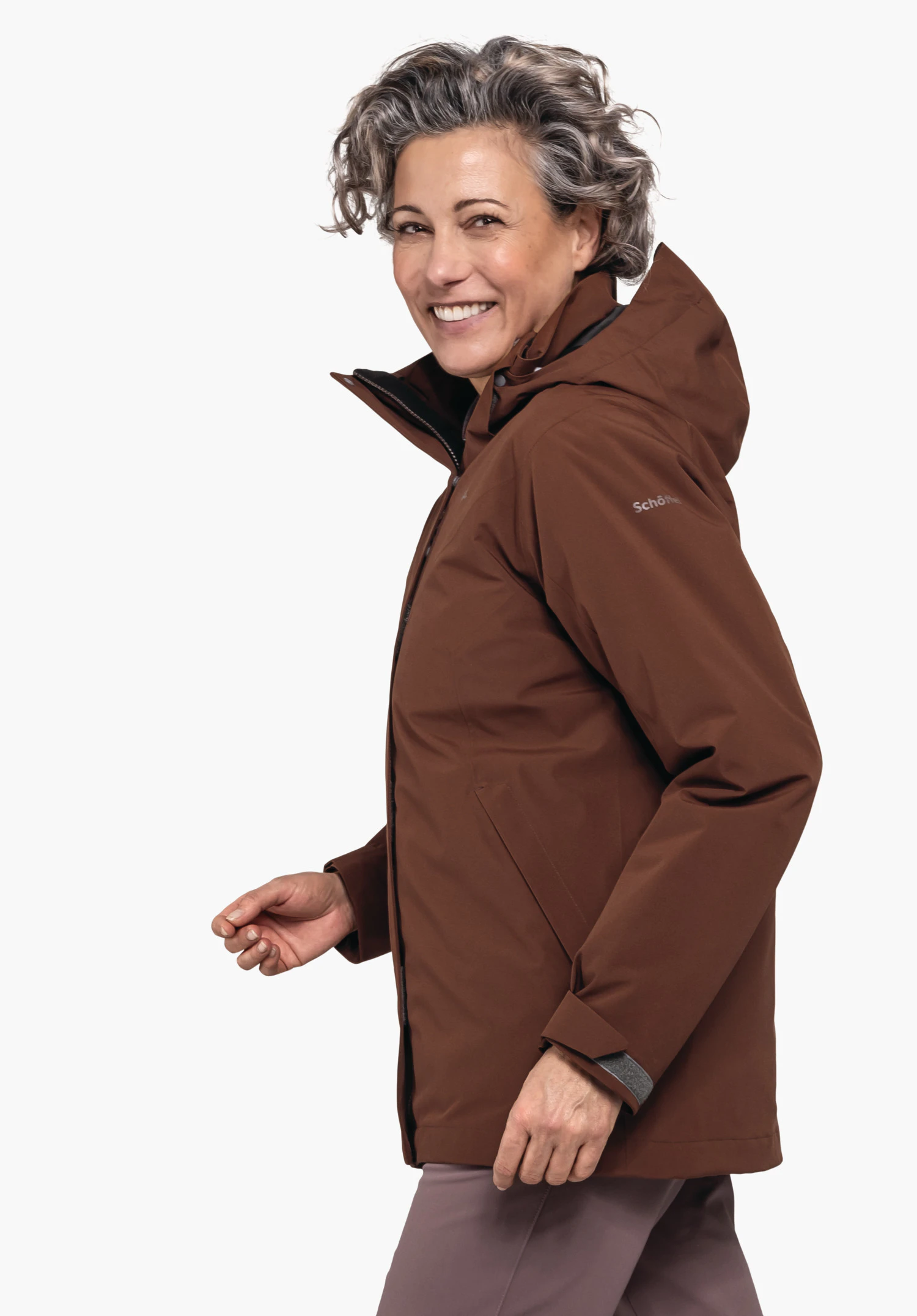 3in1 Jacket Style Tamina WMS dunkelrot Jacke, wird von einer lächelnden Frau seitlich getragen, sie geht; Kontext: neutraler heller Hintergrund. Text auf Ärmel: "Schöffel".