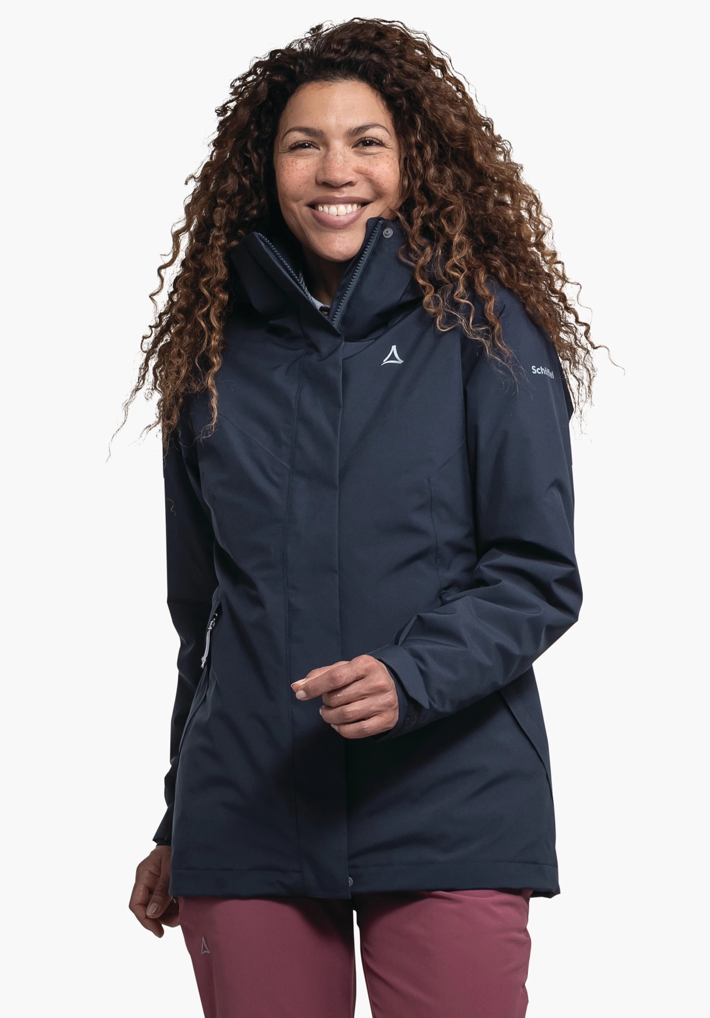 3in1 Jacket Style Tamina WMS dunkelblaue Jacke mit Schöffel-Logo vorn; Frau trägt sie lächelnd, eine Hand leicht erhoben; neutraler weißer Hintergrund. Text auf Ärmel: Schöffel.