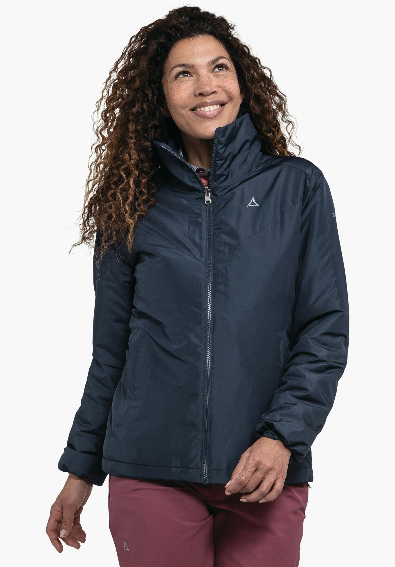 3in1 Jacket Style Tamina WMS veste femme bleu foncé avec logo Schöffel, portée par une personne souriante regardant vers le haut; col montant et fermeture éclair visible; pantalon rouge; fond blanc.