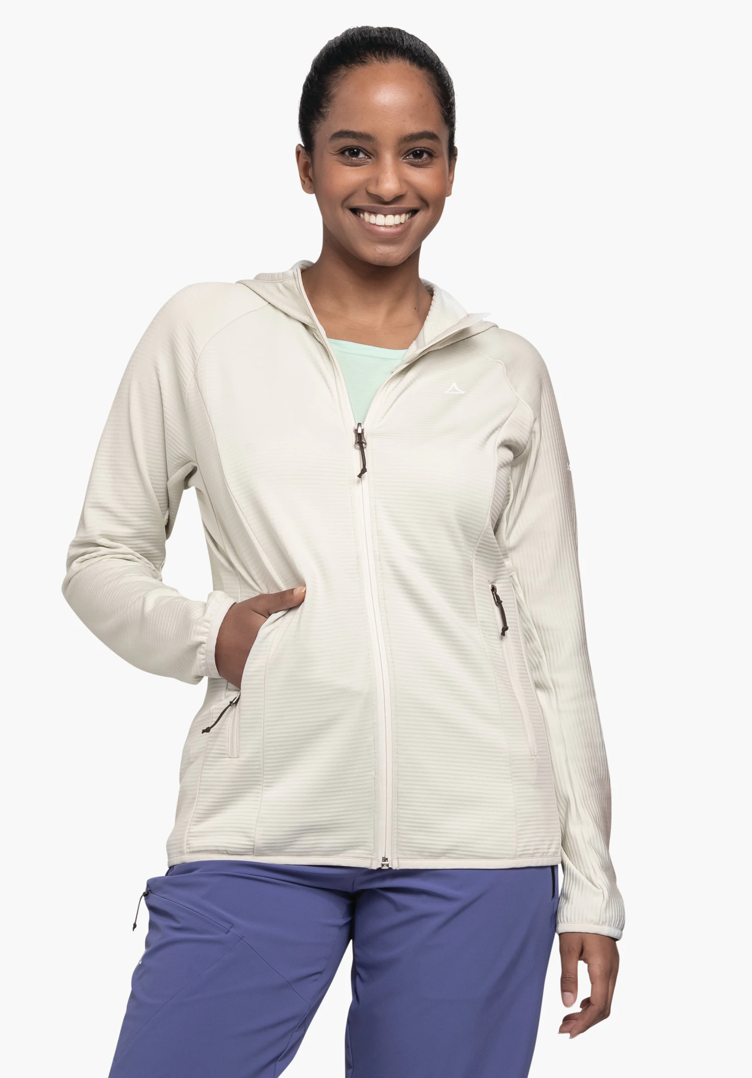 Fleece Hoody Style Cascata WMS, porté par un mannequin regardant l'objectif de face avec la main droite dans la poche latérale. La veste de couleur natur présente une fermeture éclair intégrale et le logo Schöffel sur la poitrine gauche, photographiée sur un fond neutre.