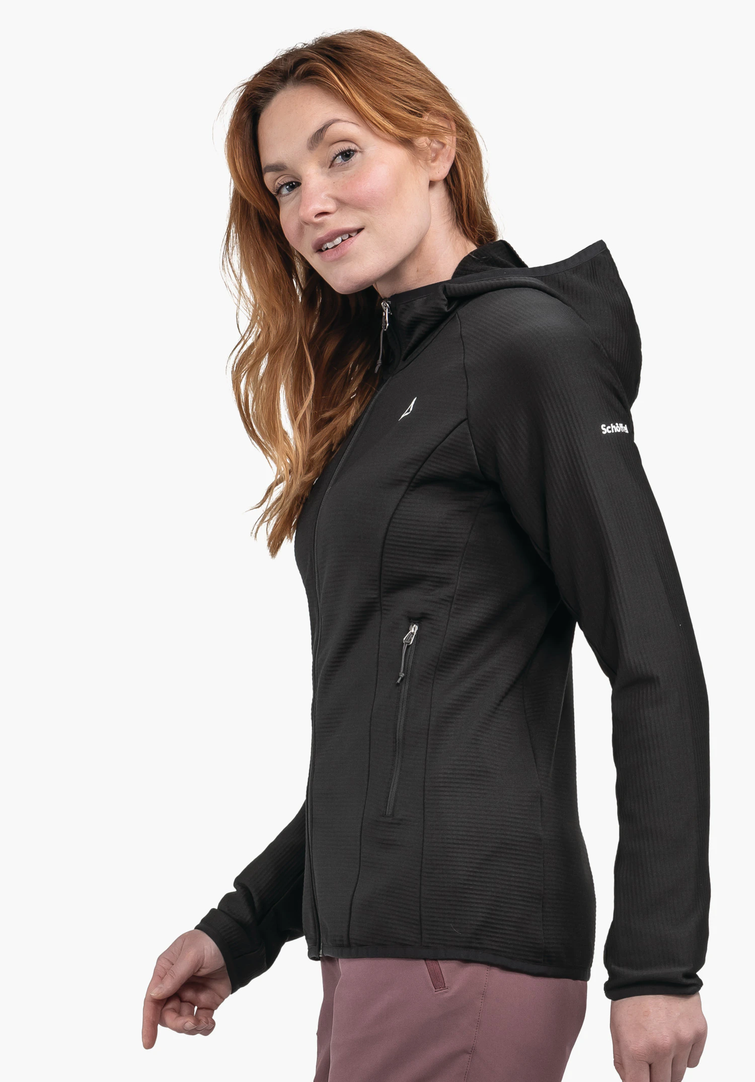 Fleece Hoody Style Cascata WMS veste à capuche noire très foncée avec logo Schöffel sur la poitrine, portée par une femme regardant par-dessus l’épaule; debout devant fond clair. Texte: "Schöffel".