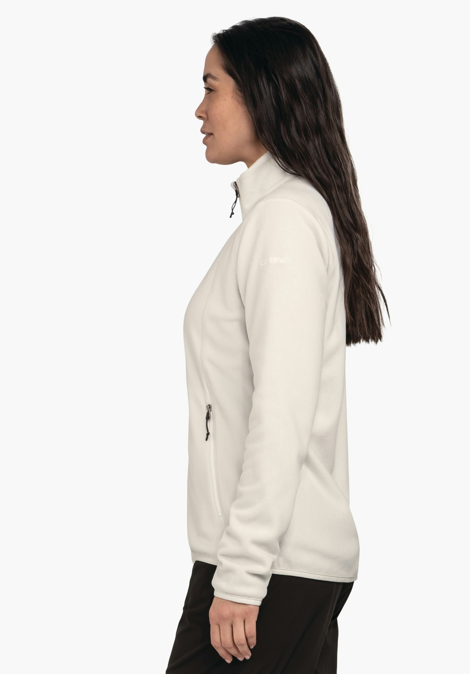 Fleece Jk Style Ash WMS weiß hell Fleecejacke, getragen von Frau im Profil; sie steht ruhig mit lockeren Armen, Reißverschluss hochgezogen, vor einfarbig hellem Hintergrund. Text auf Ärmel: "Schöffel".