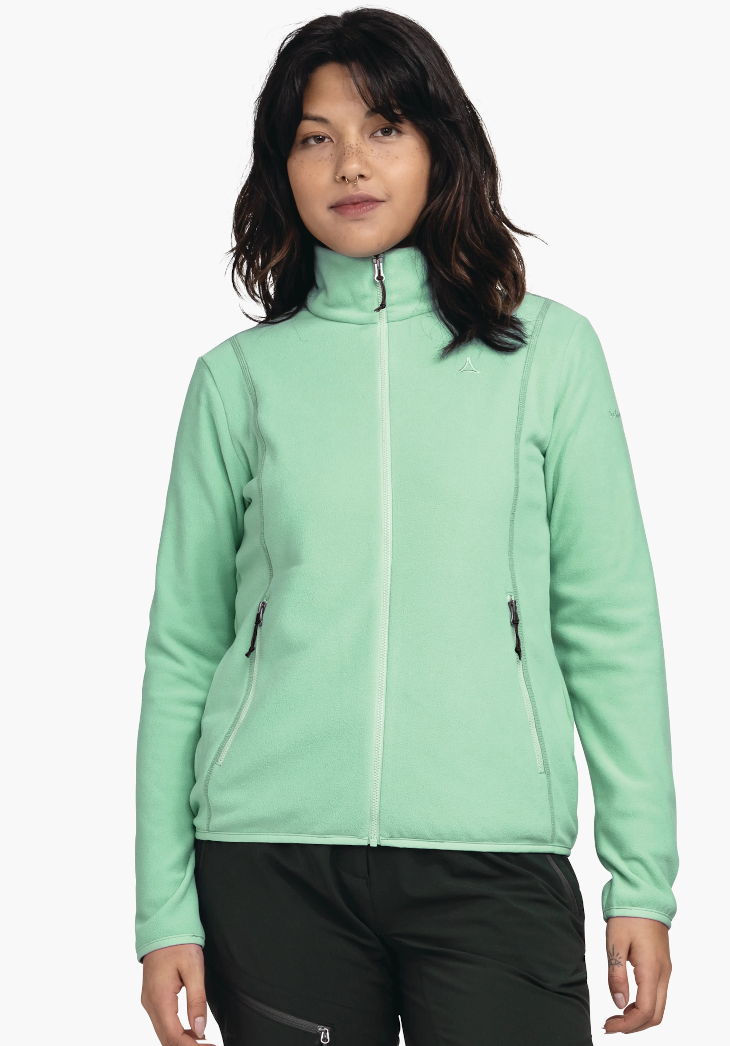 Fleece Jk Style Ash WMS light green fleece jacket worn front-facing; zip closed, two side zip pockets, high collar; small Schöffel logo on the left chest; person standing against a white background.