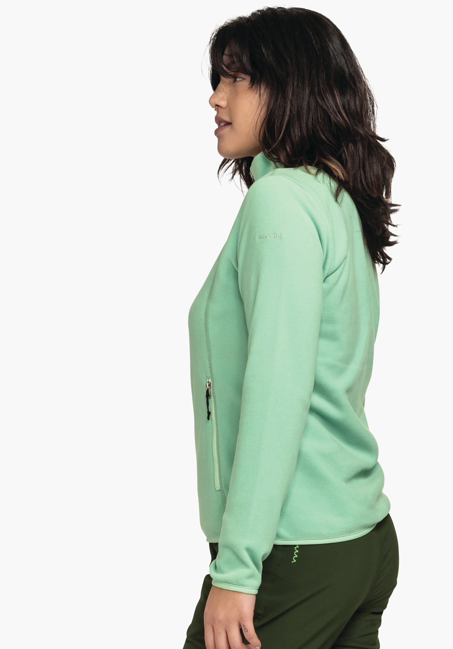 Fleece Jk Style Ash WMS light green fleece jacket worn side-on by a person; side zip pocket with black zipper, dark green trousers; white background; embroidery "schöffel" on left upper arm.