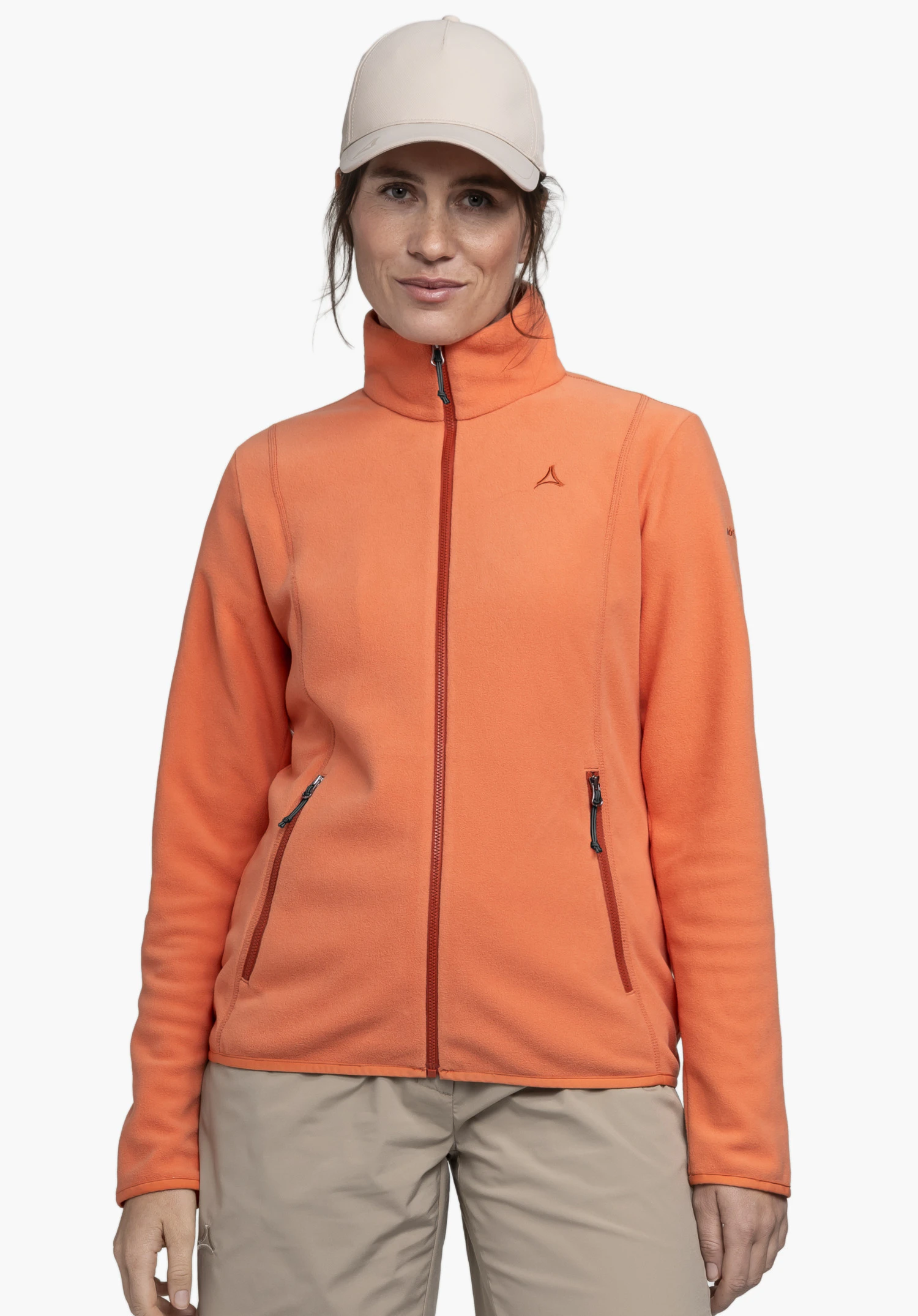 Fleece Jk Style Ash WMS is worn by a model standing facing forward. The orange jacket features a full-length zip, two side pockets and the Schöffel logo on the left chest, photographed against a neutral background.