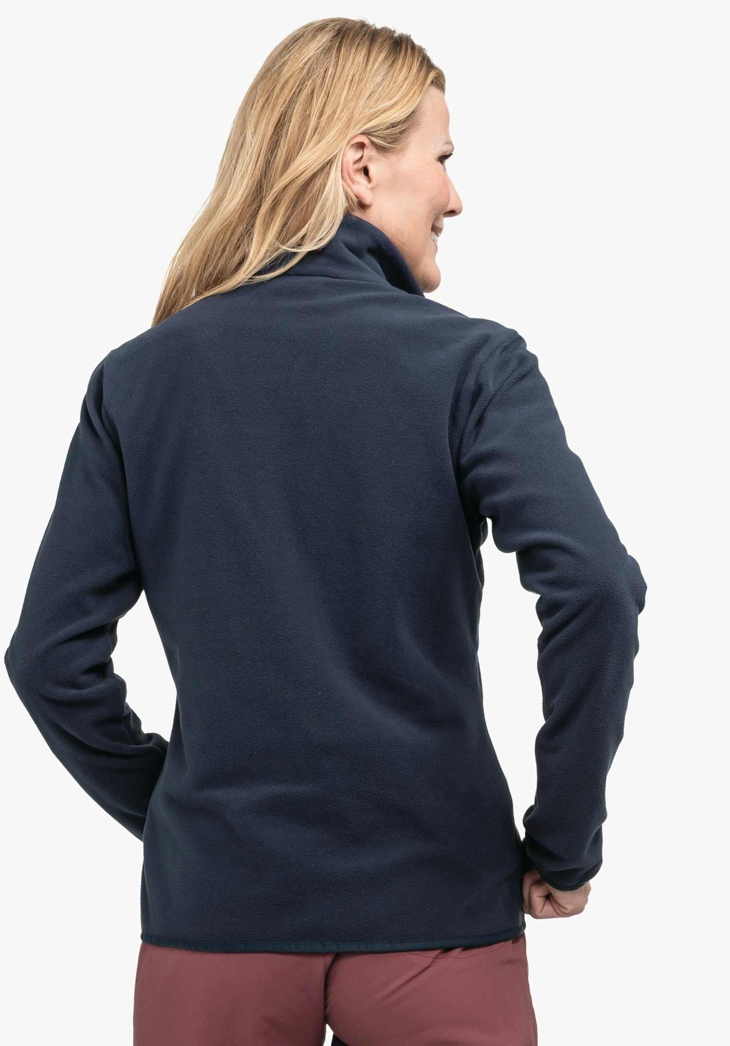 Fleece Jk Style Ash WMS dark blue fleece jacket worn from the back by a woman; she stands slightly angled with hands on hips, smiling; light neutral background.