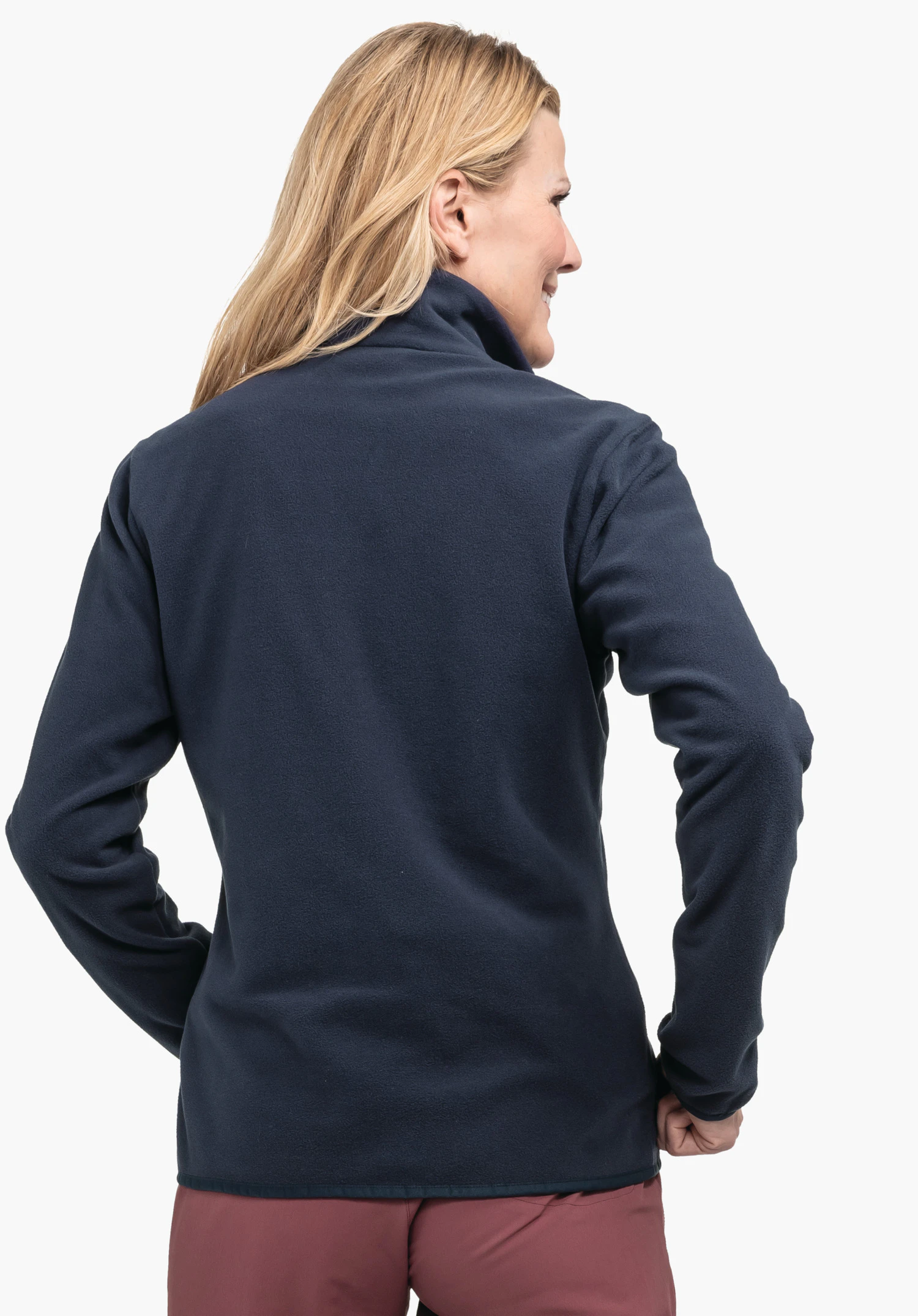 Fleece Jk Style Ash WMS donkerblauwe fleecejas, van achteren gedragen door een vrouw; zij staat licht zijwaarts met handen op de heupen en glimlacht, voor een lichte neutrale achtergrond.