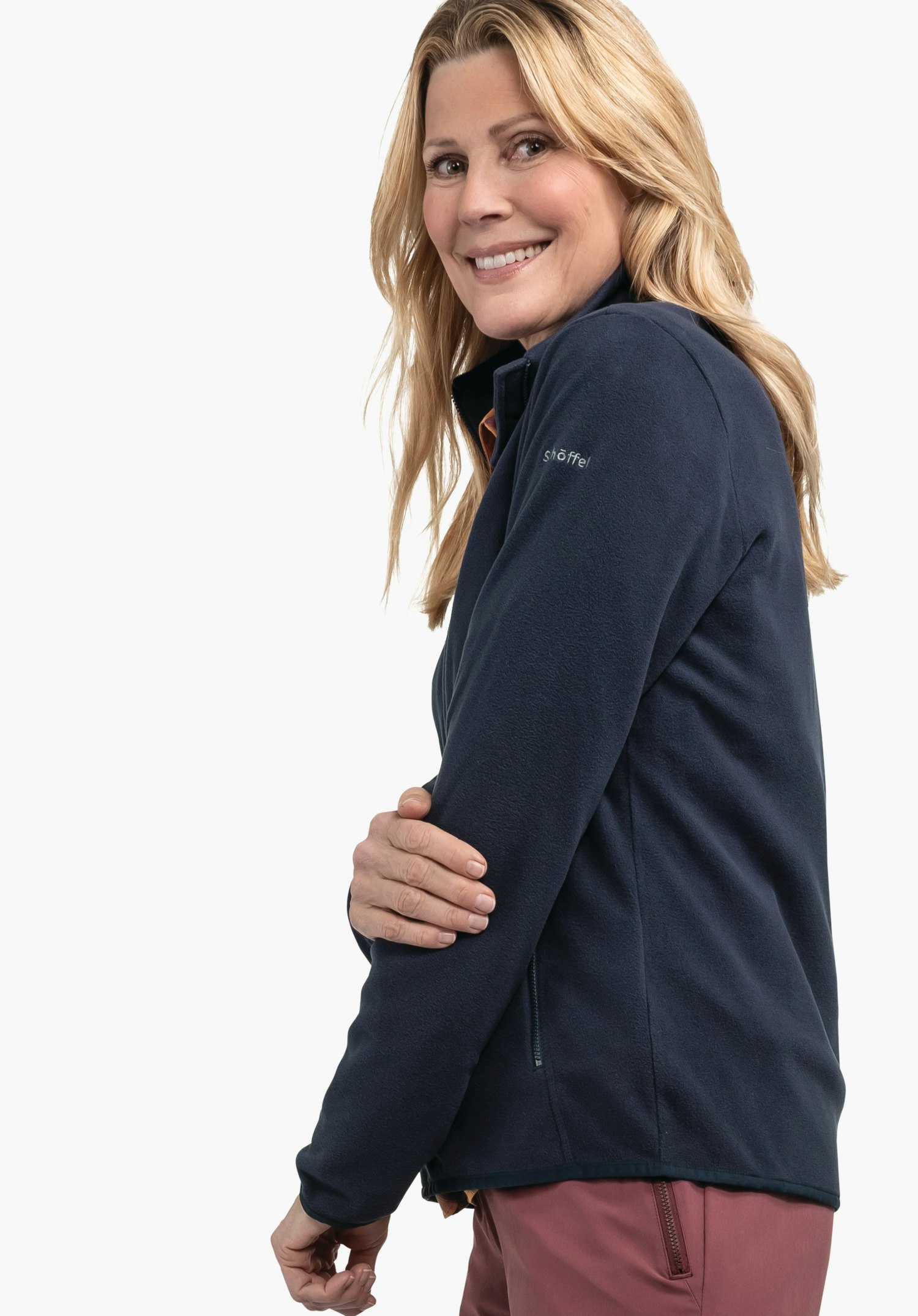 Fleece Jk Style Ash WMS dark blue fleece jacket; woman smiles, holds her upper arm and stands in front of a white background. Text on sleeve: "schöffel".
