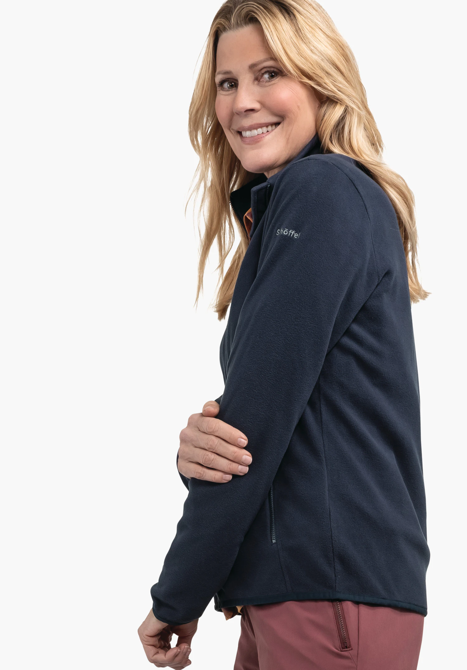 Fleece Jk Style Ash WMS donkerblauwe fleecejas; vrouw glimlacht, houdt haar bovenarm vast en staat voor een witte achtergrond. Tekst op de mouw: "schöffel".