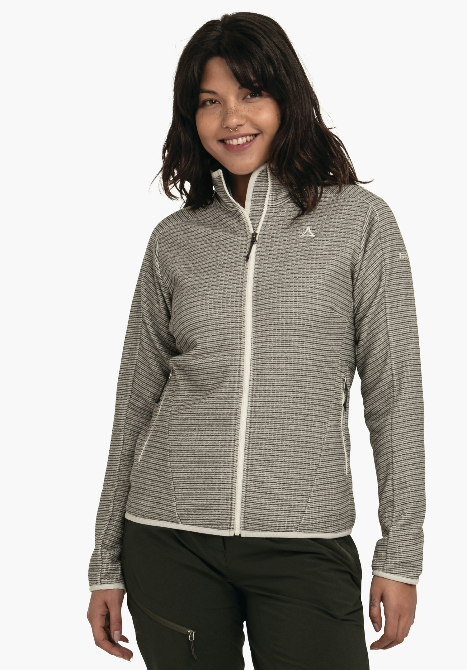 CIRC Fleece Jk Style Terxa WMS Veste portée par une femme souriante; veste zippée avec logo Schöffel, debout devant un fond blanc, associée à un pantalon vert foncé.