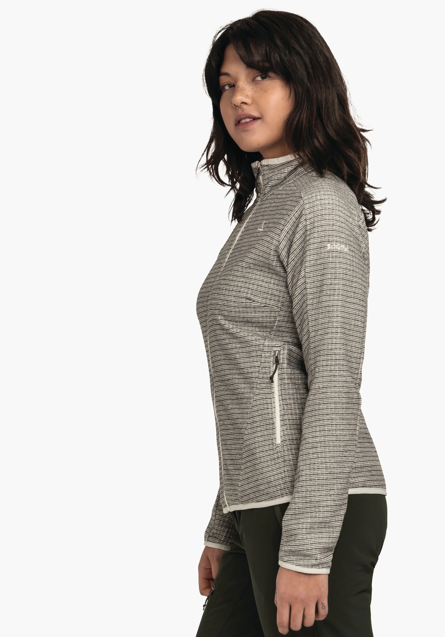 CIRC Fleece Jk Style Terxa WMS veste gris clair finement rayée avec fermeture éclair (logo Schöffel) portée par une femme debout de profil et souriant légèrement; fond blanc. Texte: "Schöffel".