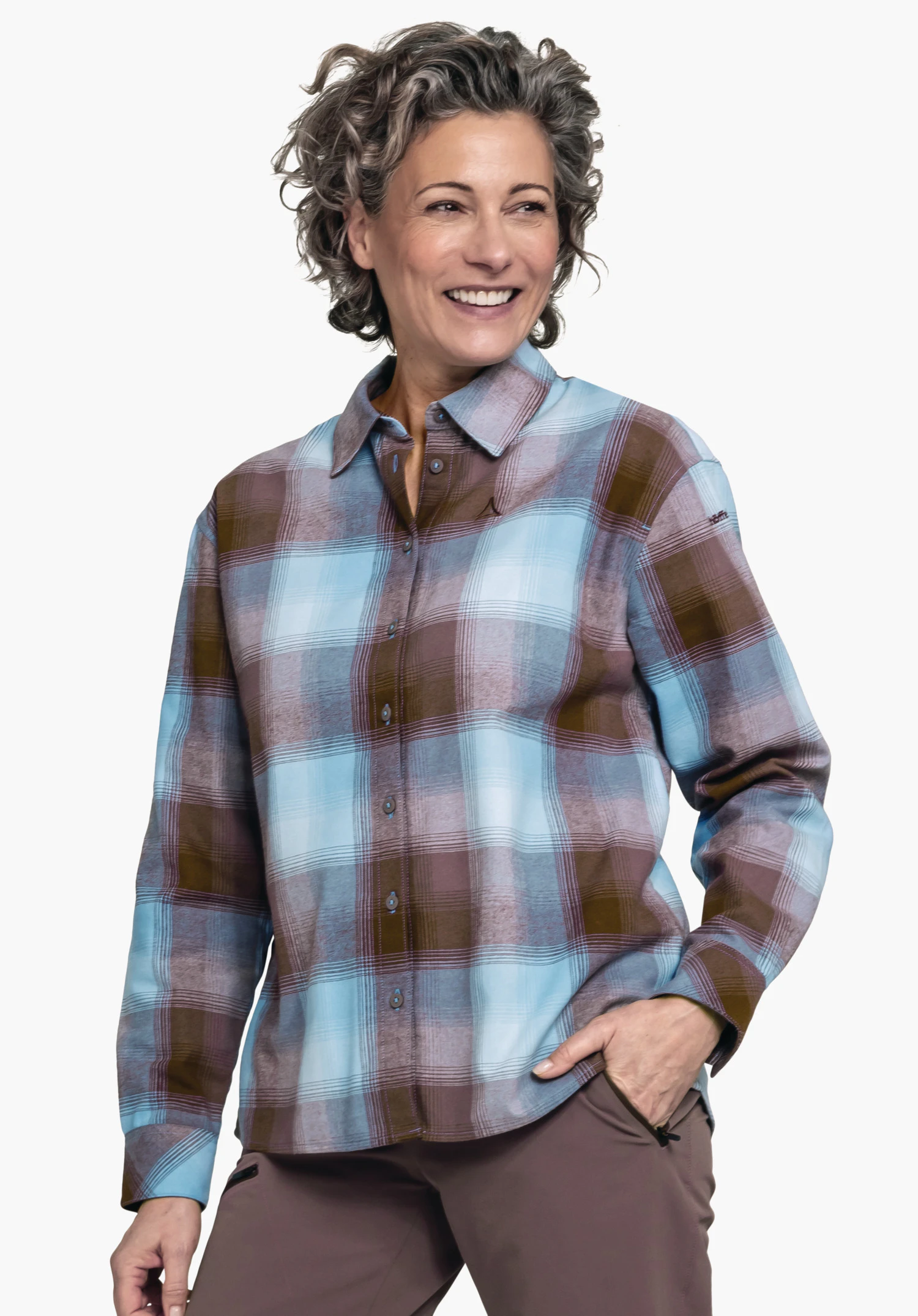 Blouse Style Limedes WMS Chemise à carreaux bleu clair et orange foncé, portée par une personne souriante avec la main droite dans la poche du pantalon; logo Schöffel sur la poitrine gauche; fond clair neutre.