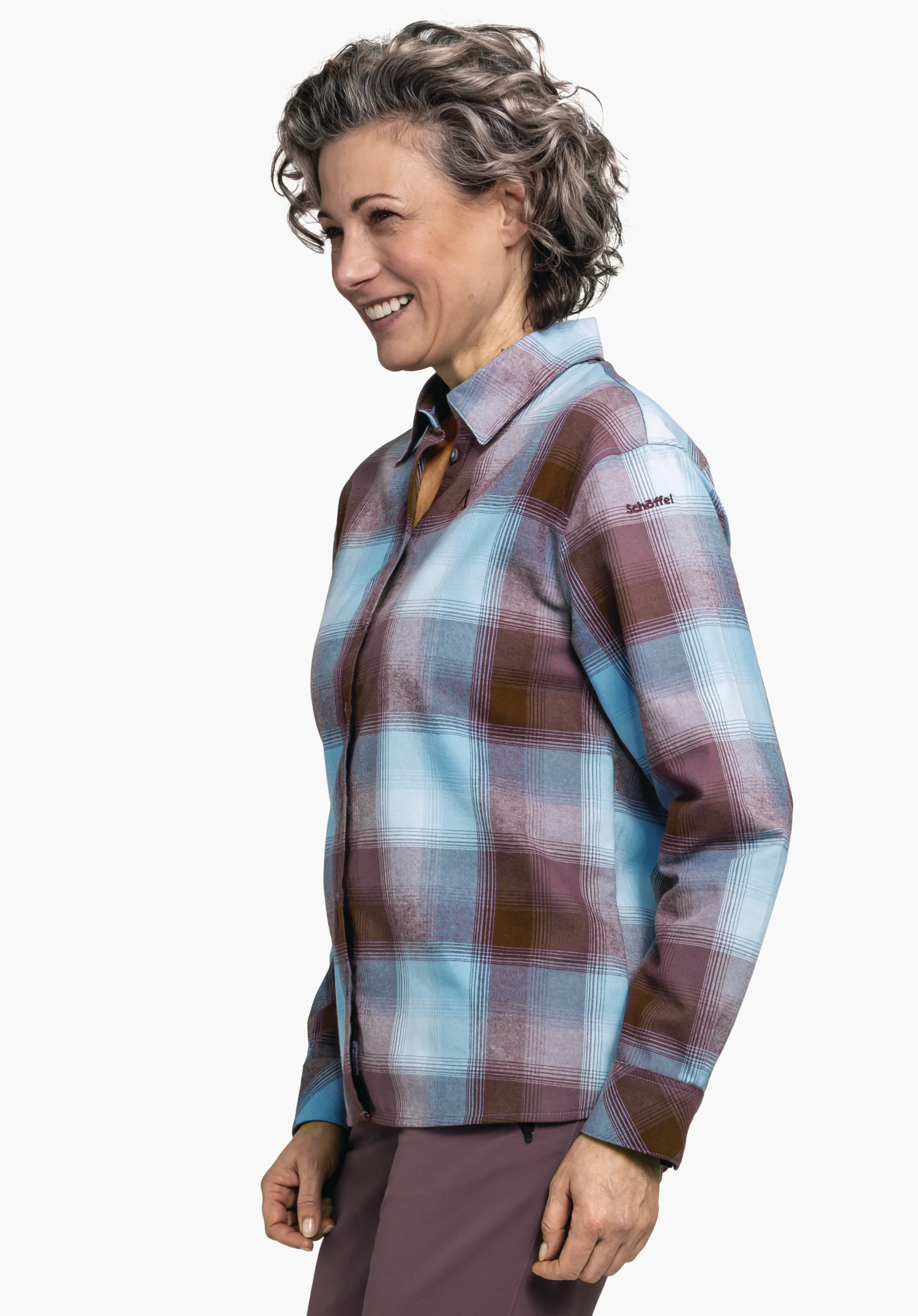 Blouse Style Limedes WMS geruite blouse (lichtblauw, bruin, paars), vrouw glimlacht en staat zijwaarts voor een lichte achtergrond; op de mouw staat "Schöffel".
